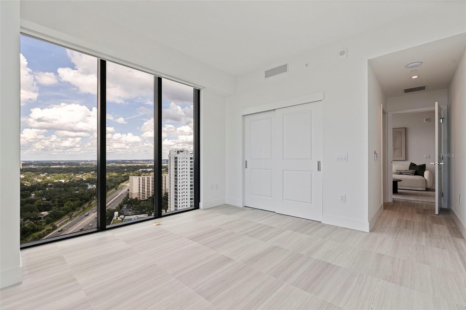 Bedroom Two sits just beyond the den, wrapped in natural light with motorized shades for privacy at a touch.