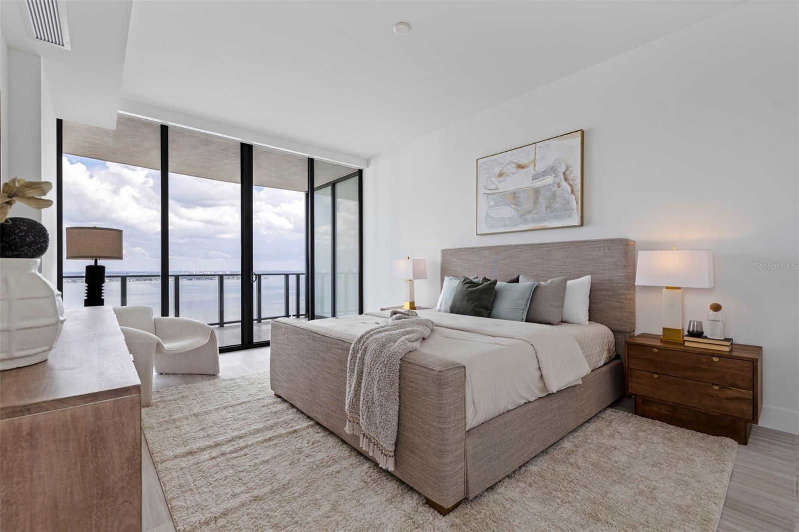 A serene primary suite with private balcony access and sunrise views over the bay.