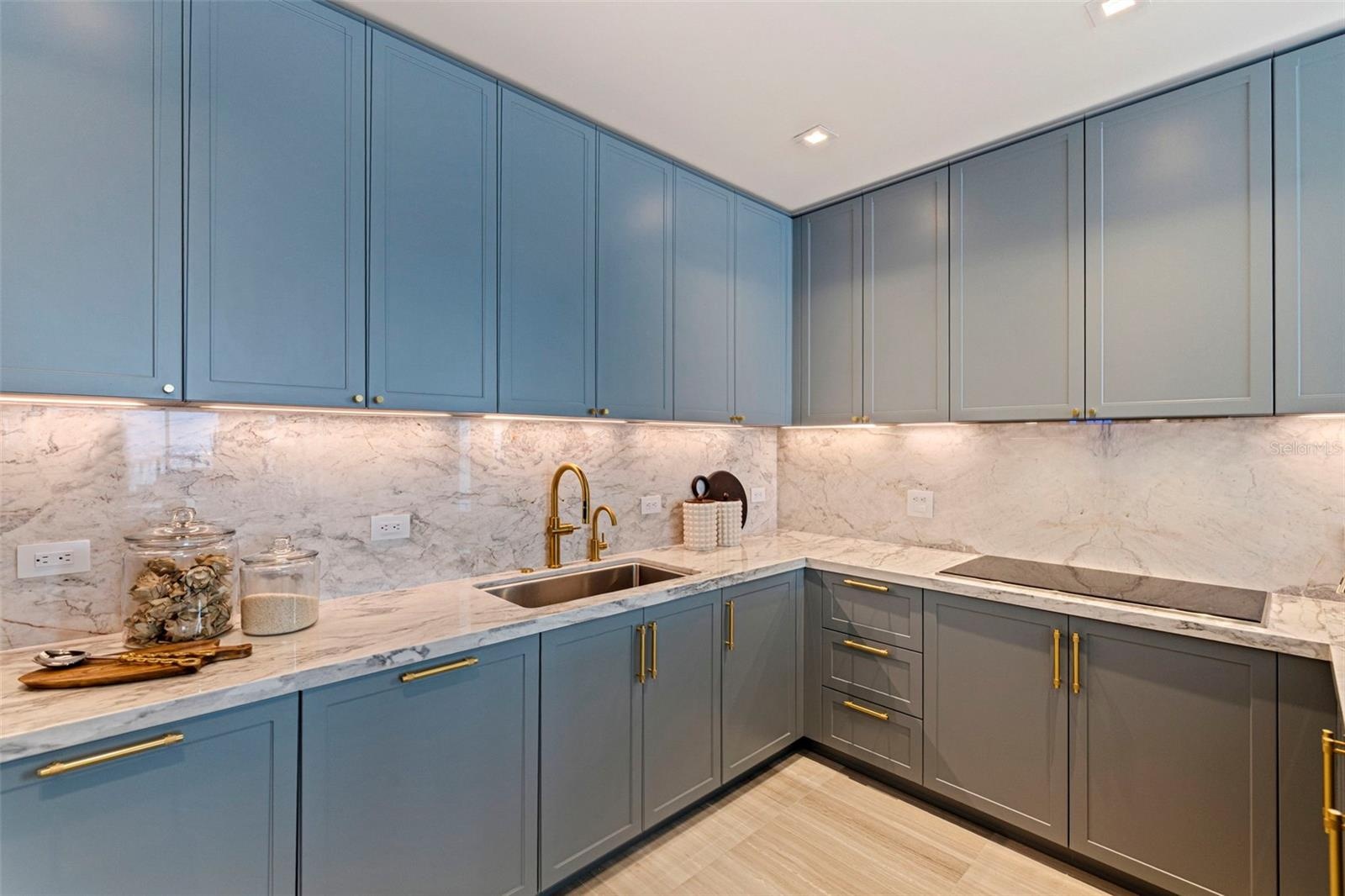 Italian ItalKraft cabinetry, marble surfaces and warm under-cabinet illumination.