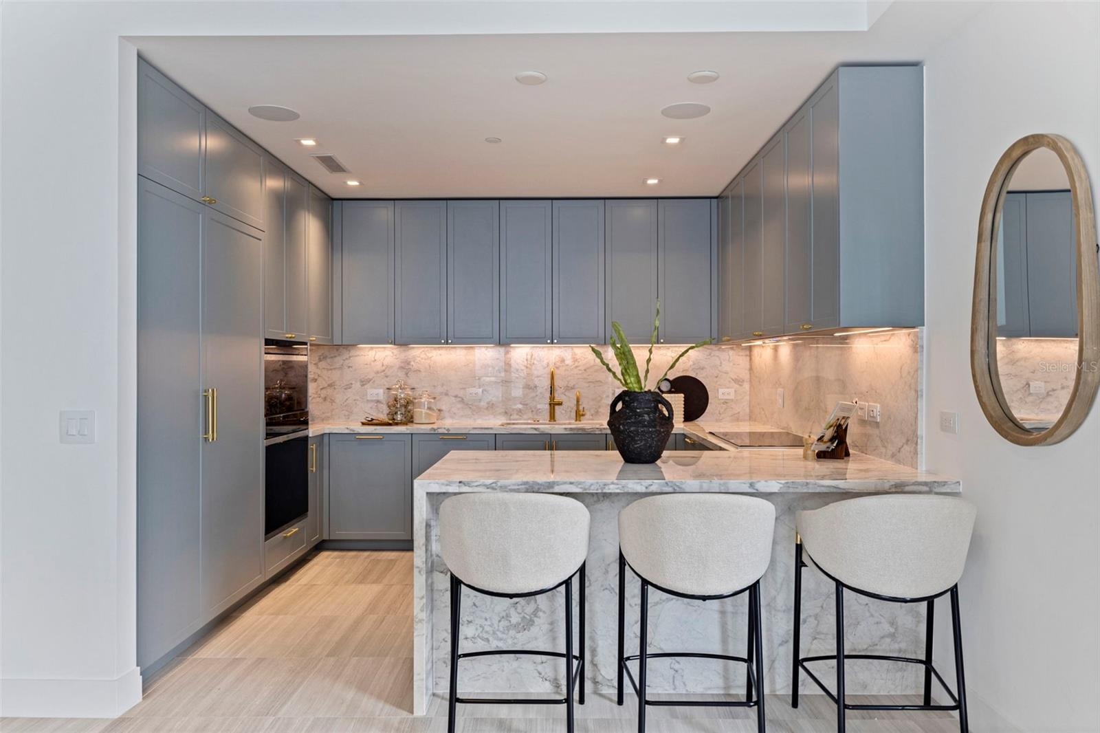 Ritz-Carlton blue cabinetry, luminous marble, and refined detailing give the kitchen its unmistakable presence.