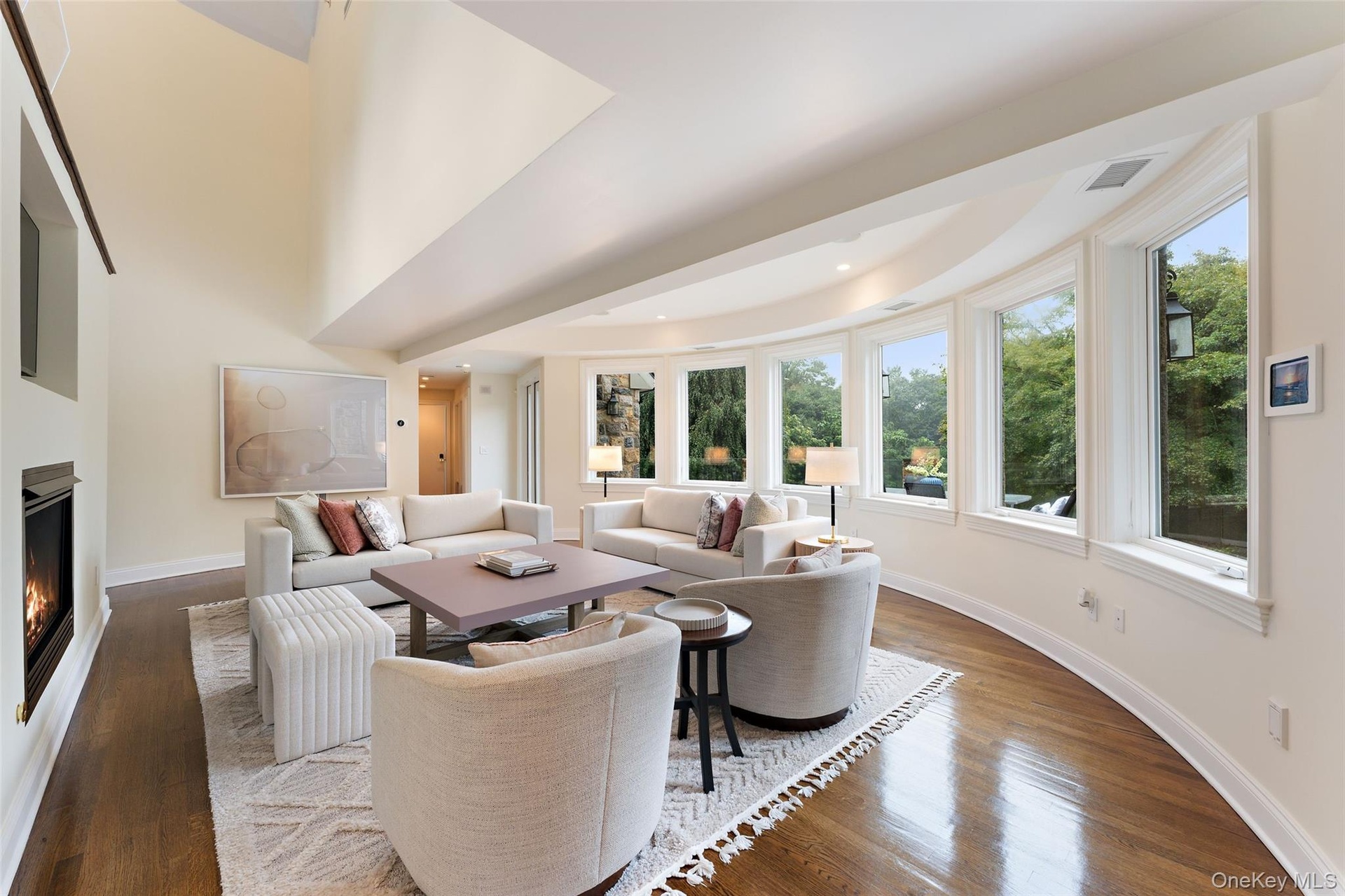 Family room with wall o curved windows overlooking patio and garden