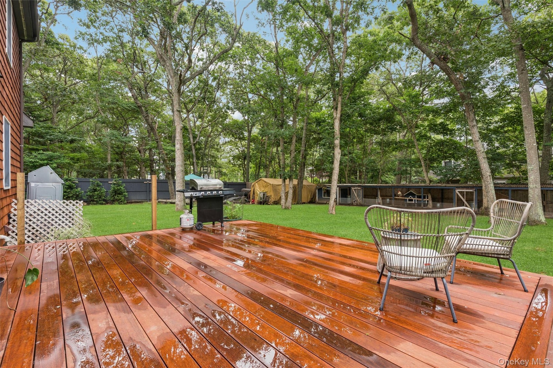 Expansive wooden deck with natural wood siding, leading to a manicured lawn framed by mature trees