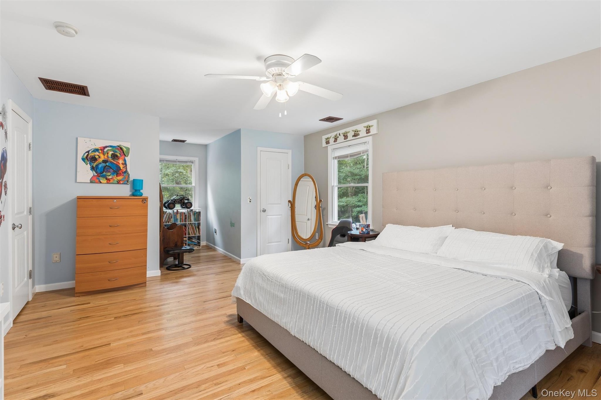 Hardwood flooring throughout, a white ceiling fan, and multiple windows providing natural light