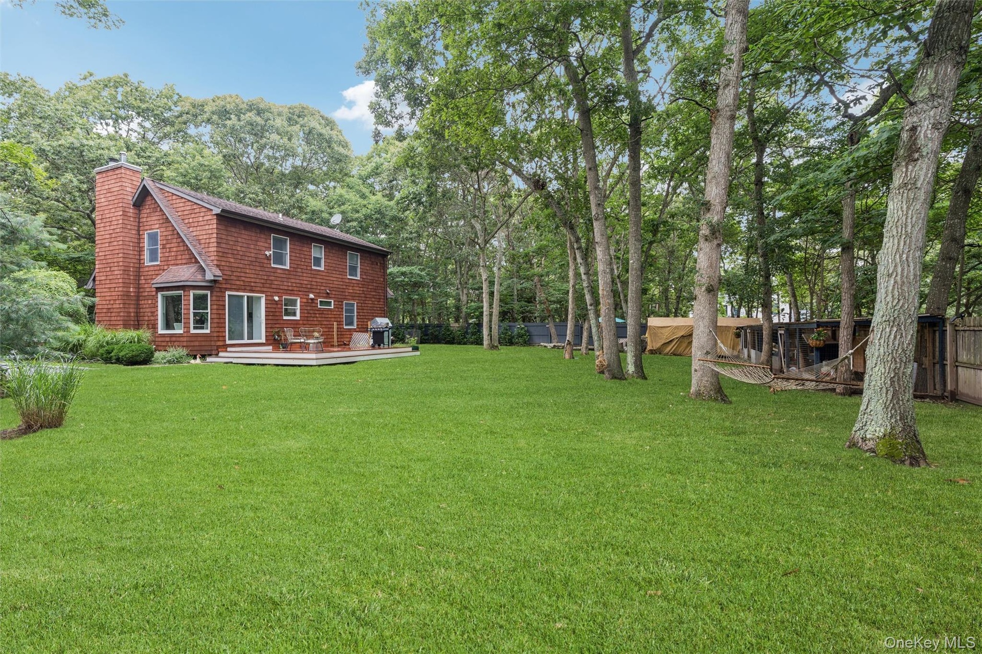 Wood-shingle exterior with a prominent brick chimney, multi-pane windows, and a rear deck
