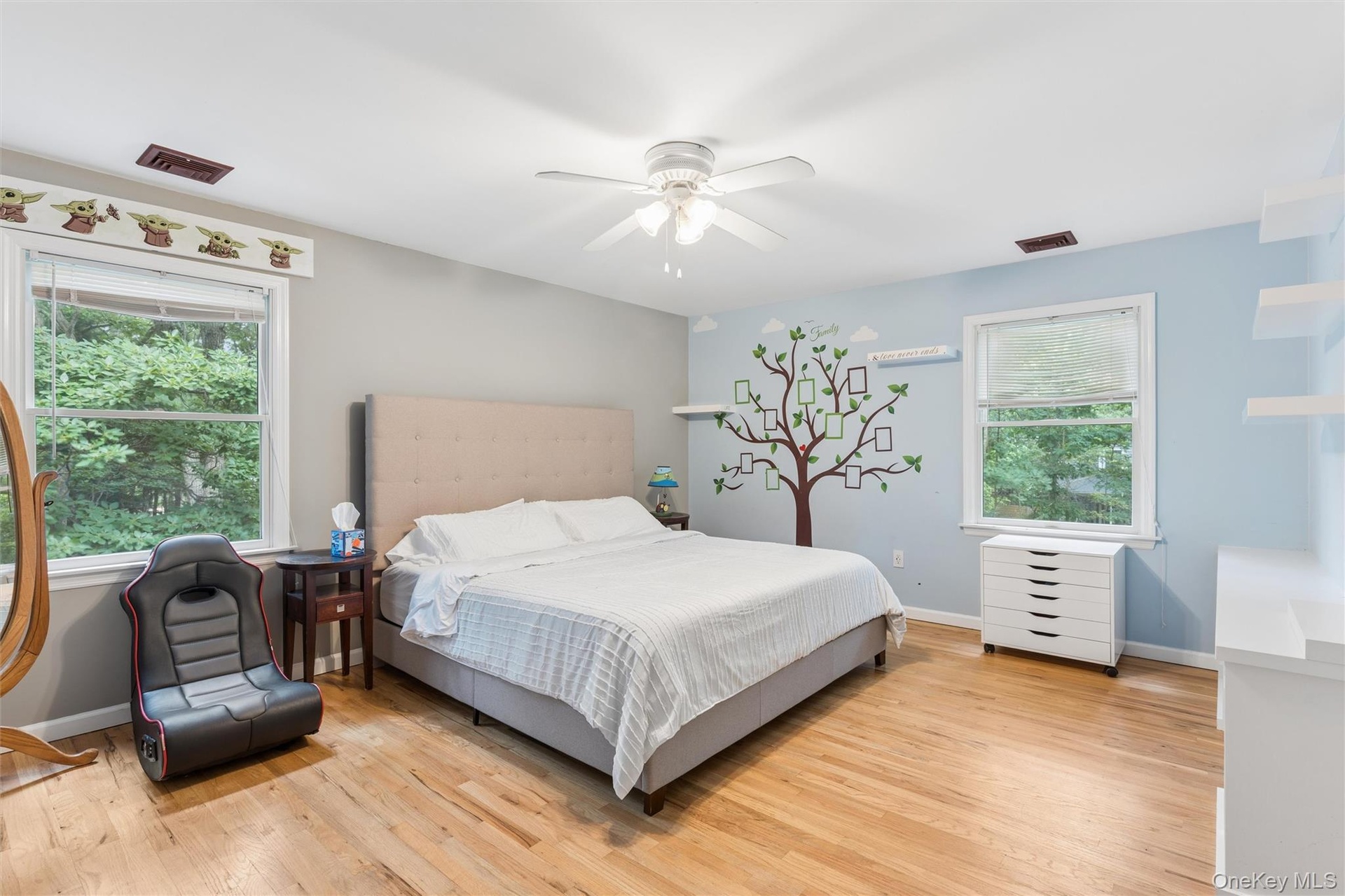 Hardwood flooring, two windows with natural light, ceiling fan with light fixture, and painted walls
