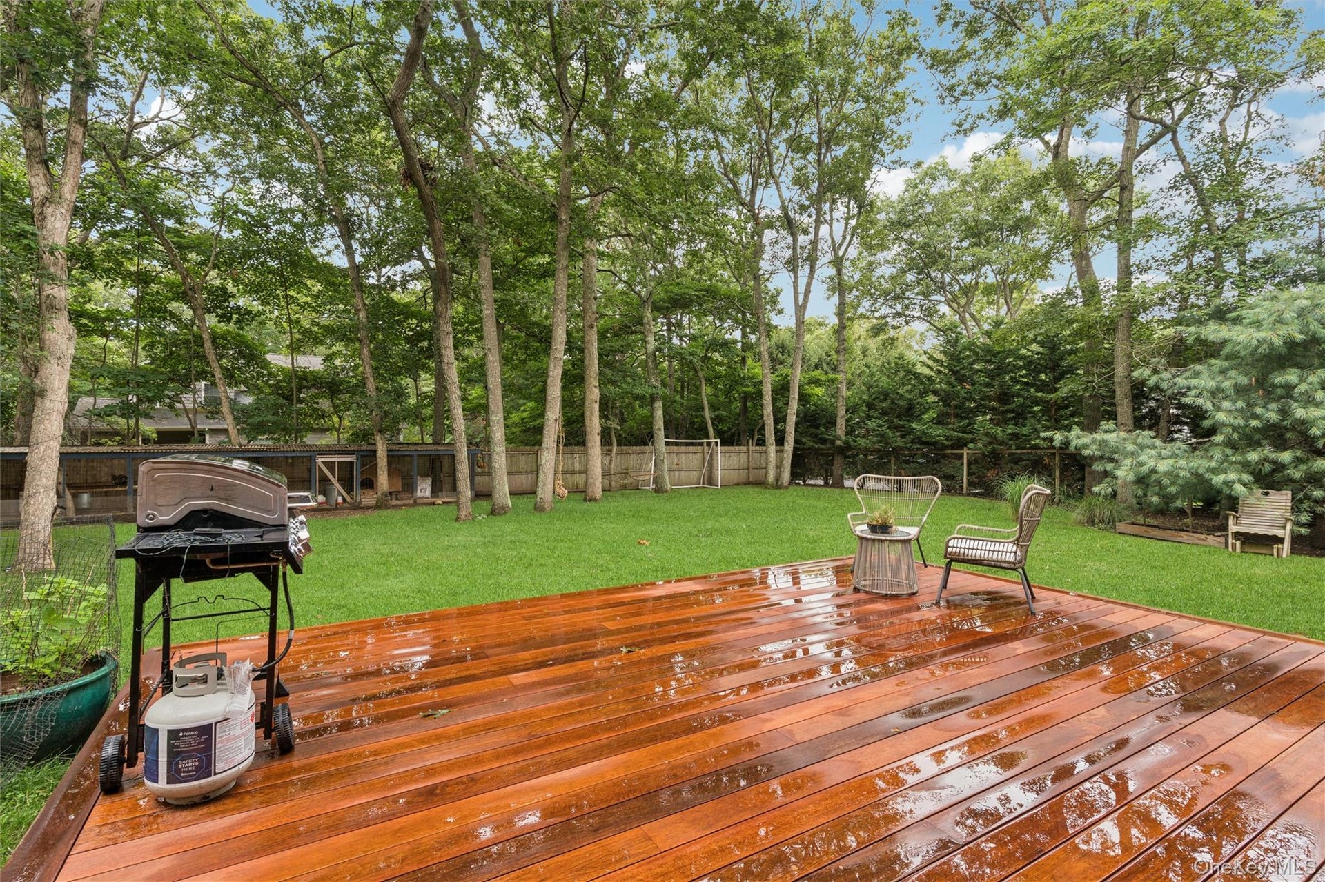 Spacious wood-finish deck with a manicured lawn and mature trees