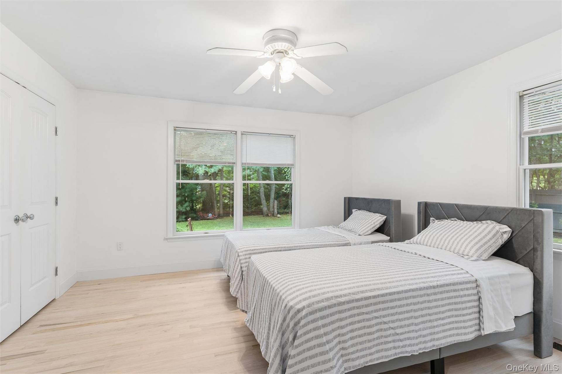 White walls, light wood-finish flooring, and a ceiling fan