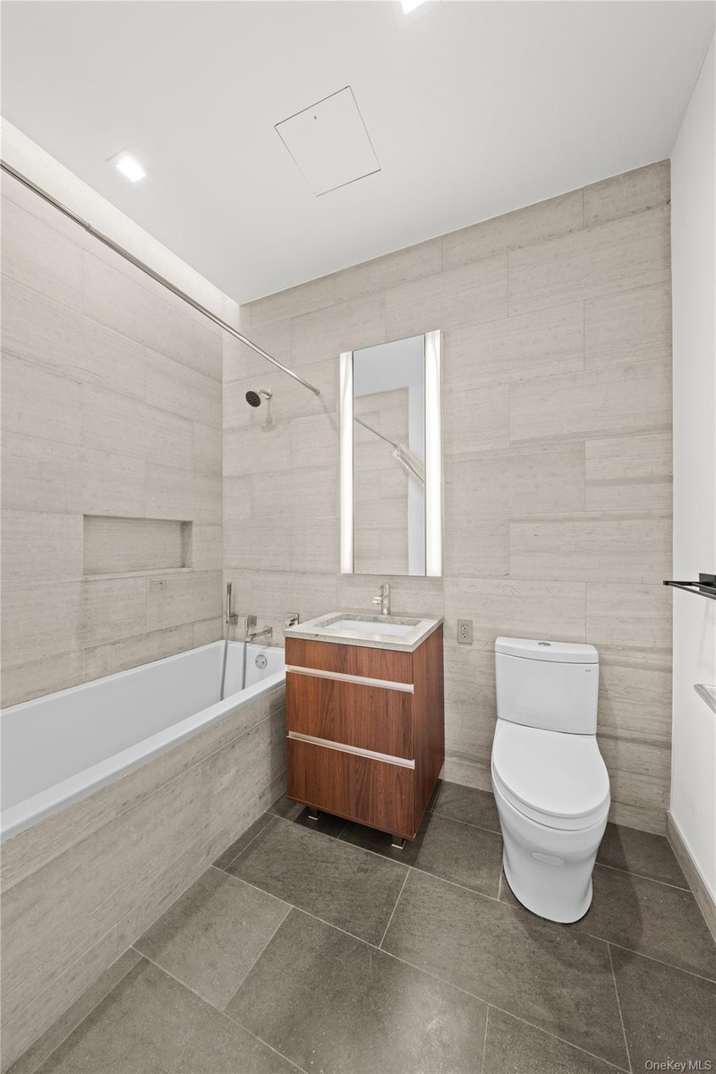 Bathroom featuring vanity, tile walls, tiled shower / bath combo, and dark tile patterned floors