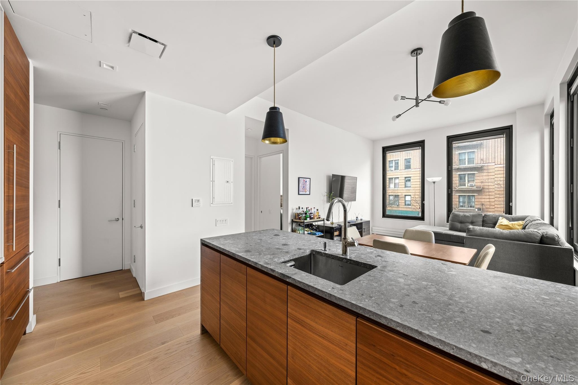 Kitchen with brown cabinetry, dark stone counters, hanging light fixtures, open floor plan, and modern cabinets