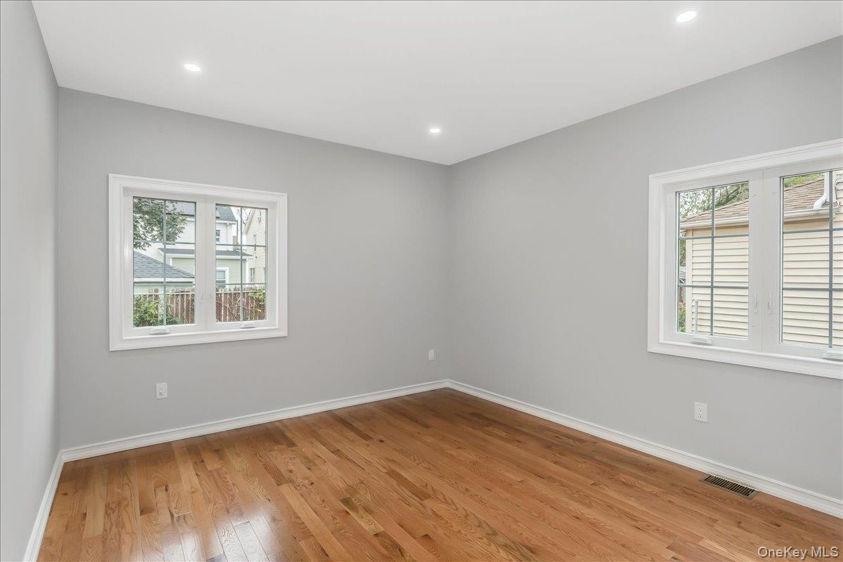 Empty room with light wood-style floors and recessed lighting
