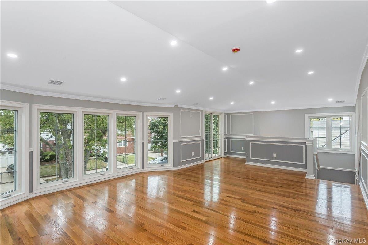 Unfurnished living room with crown molding, light wood-type flooring, a decorative wall, and recessed lighting