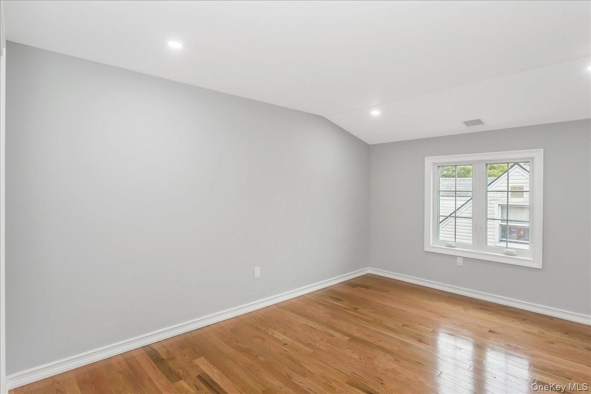Spare room featuring light wood-type flooring, recessed lighting, and vaulted ceiling