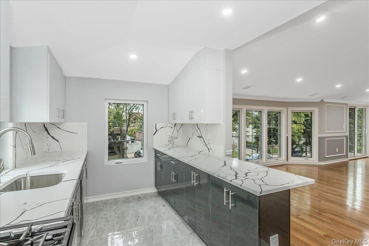 Kitchen featuring light stone counters, white cabinets, modern cabinets, and recessed lighting