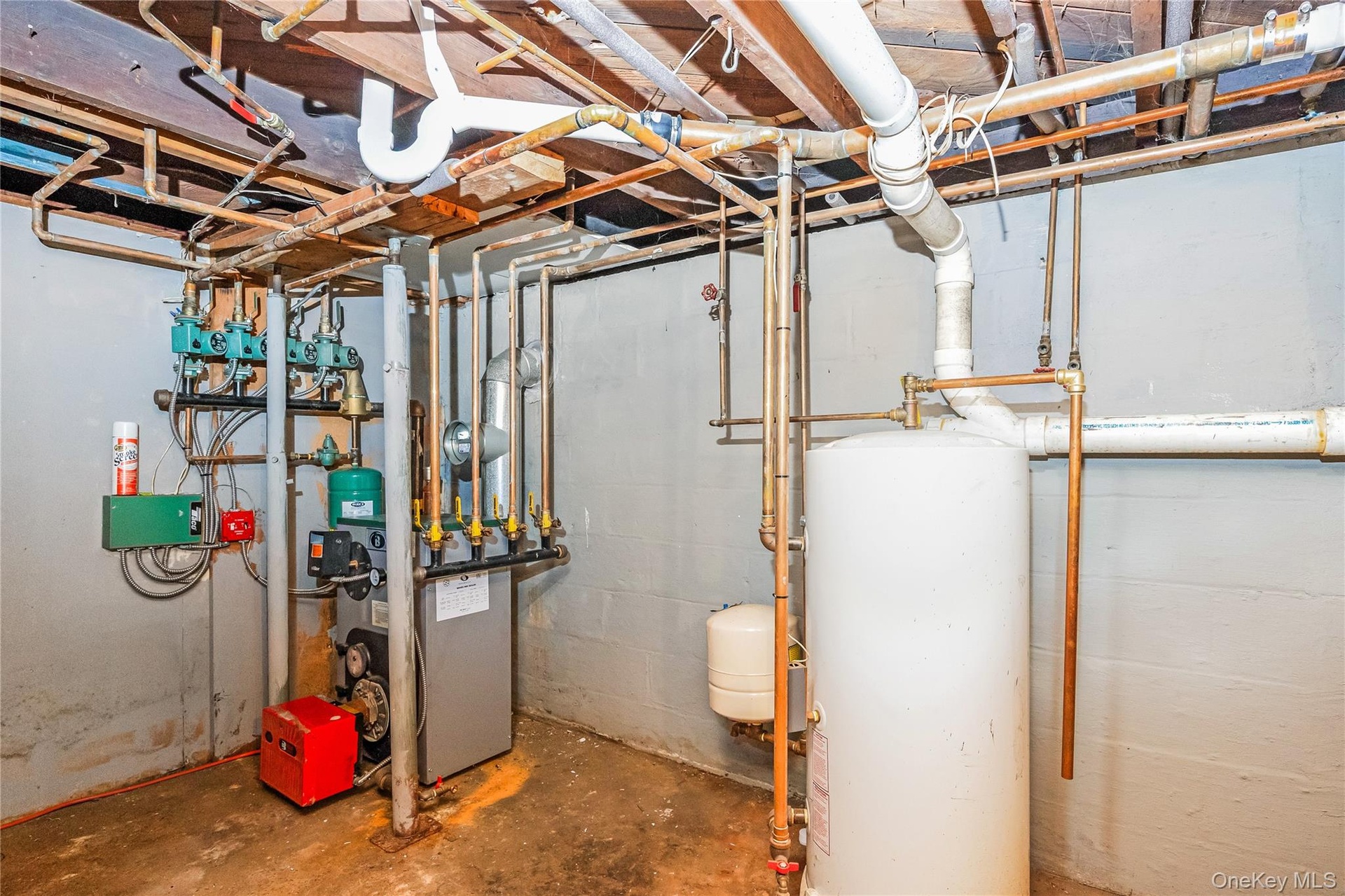 Utility area featuring a water heater, hydronic heating system, and extensive copper piping