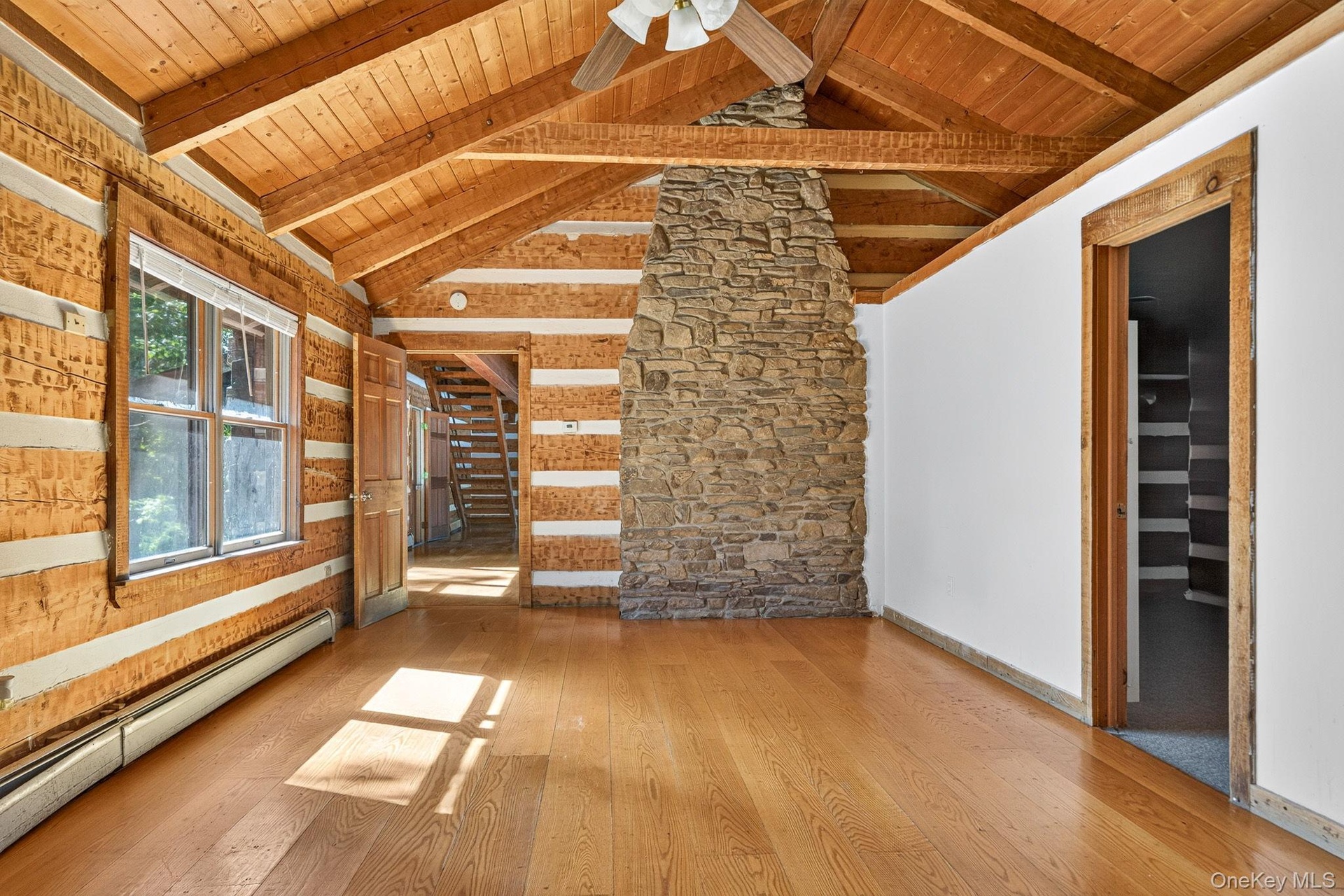 Main residence primary bedroom featuring back of family room stone fireplace.  IGenerous walk-in closet and full bathroom.