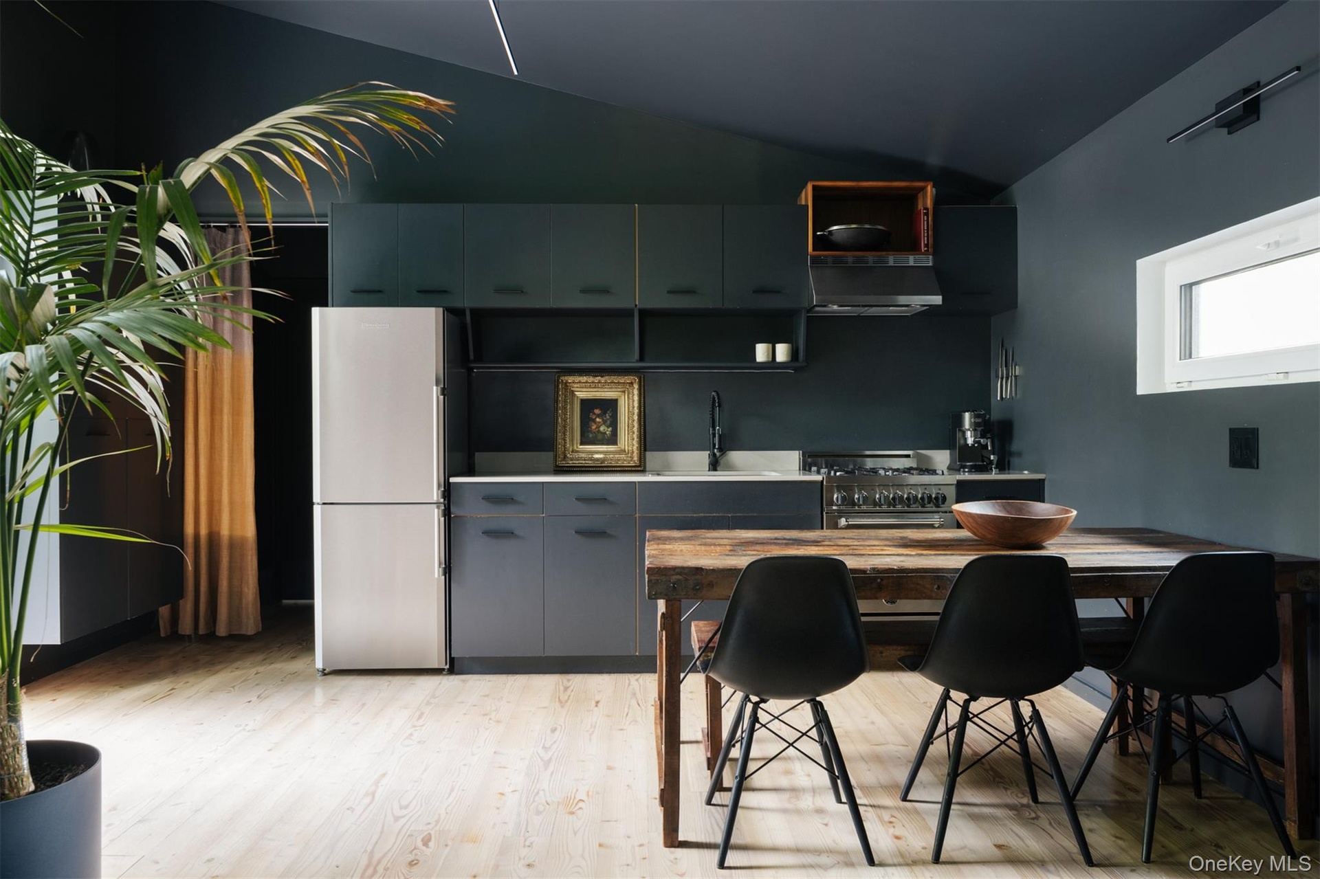 Kitchen with stainless steel appliances, light wood-type flooring, under cabinet range hood, modern cabinets, and light countertops