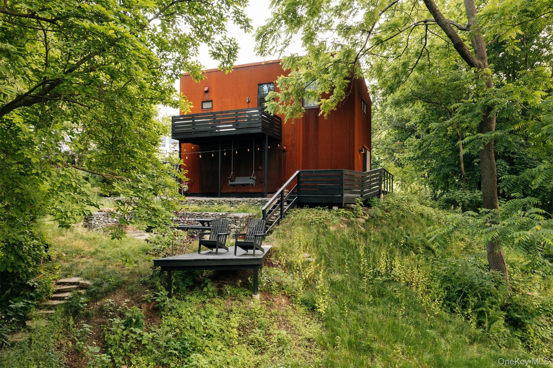 Back of property with stairway and a view of trees
