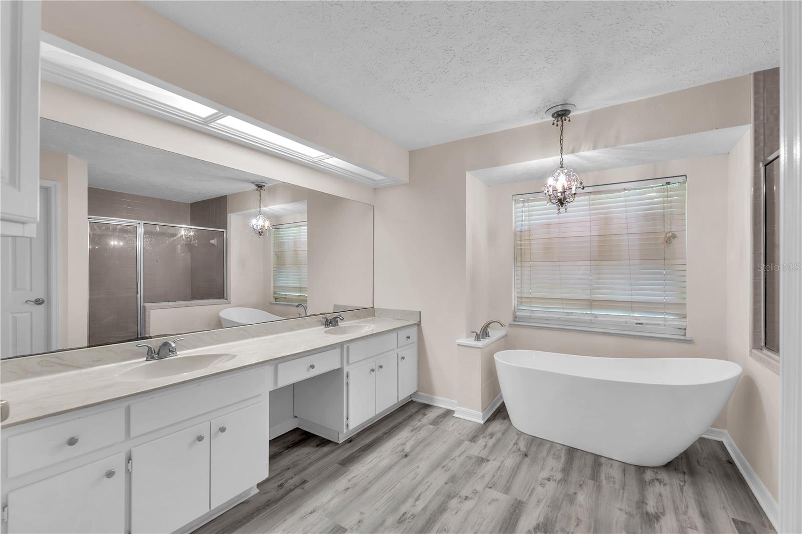 The owner's ensuite bath has a large vanity with dual sinks and plenty of storage, an elegant freestanding slipper tub, separate shower, and private w