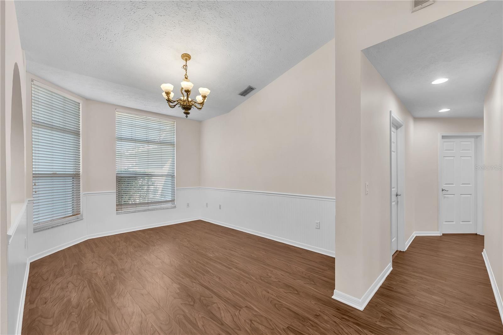 The dining room is conveniently located just off the kitchen and features charming shiplap wainscoting with a classic chair rail, adding texture and c