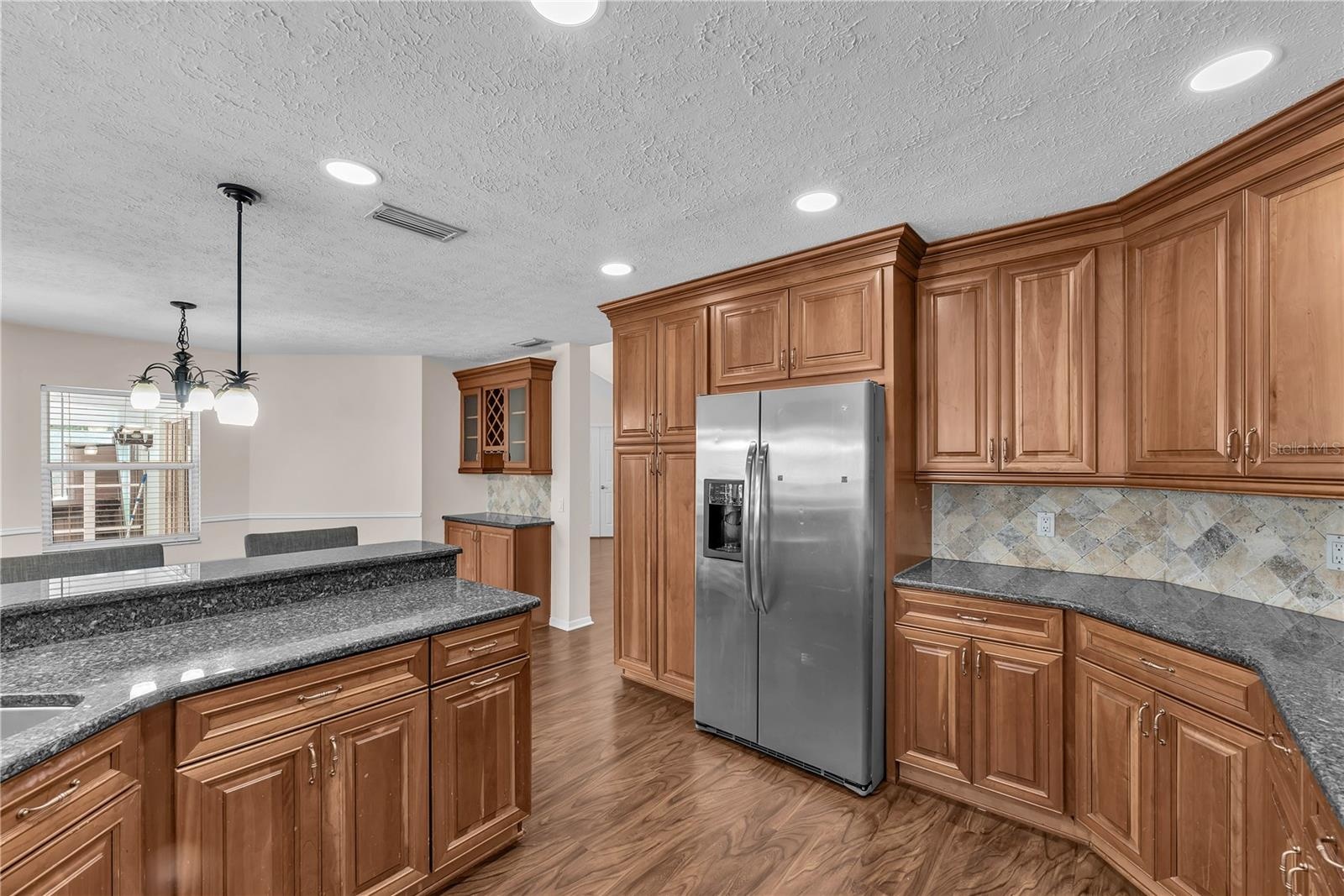 At the heart of the home, the spacious kitchen features custom wood cabinetry, Level 5 granite countertops, stone backsplash and stainless steel appli