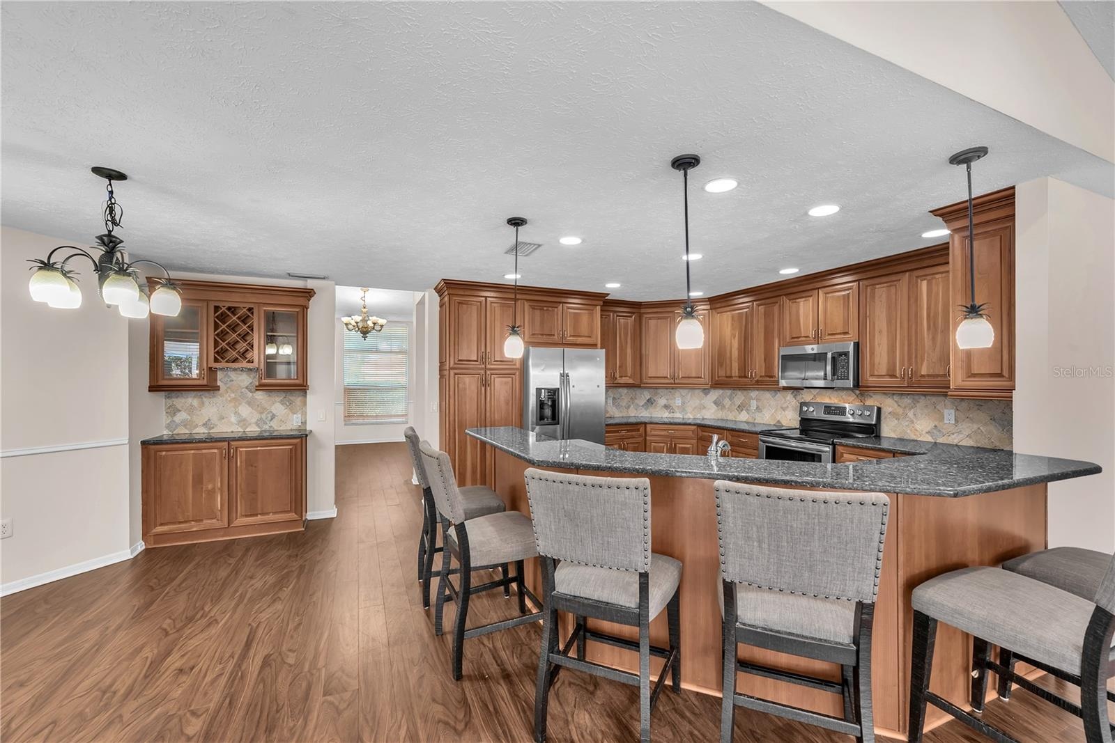 The breakfast bar provides additional seating, while a wall of cabinetry with a built-in wine rack and glass-front doors offers the perfect spot for d