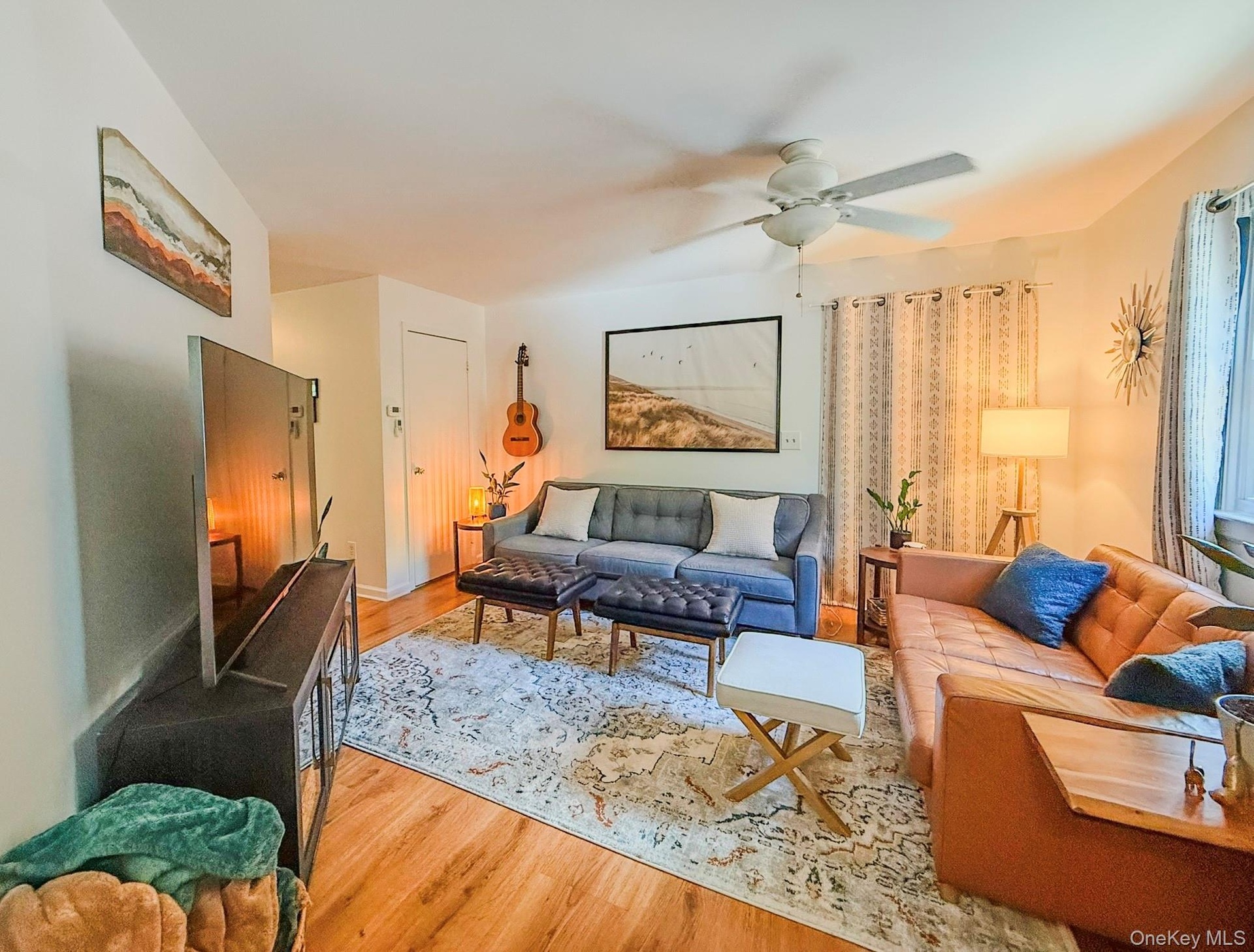 Upper Apartment  Living Room Hardwood-style flooring throughout, ceiling fan with integrated lighting, and multiple windows with vertical blinds