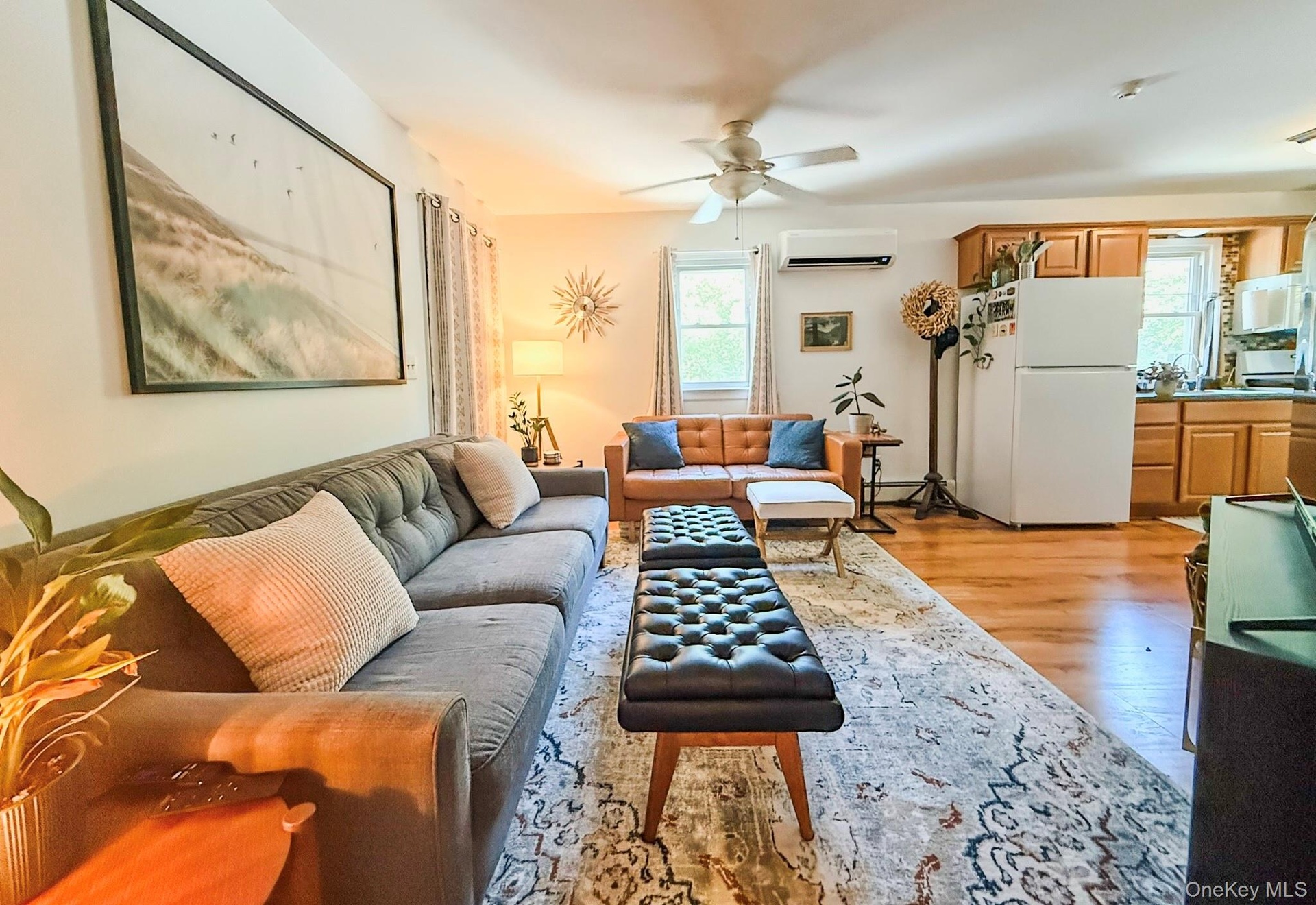 Upper Apartment  Living Room Hardwood-style flooring throughout, ceiling fan with integrated lighting, and multiple windows with vertical blinds  Livi