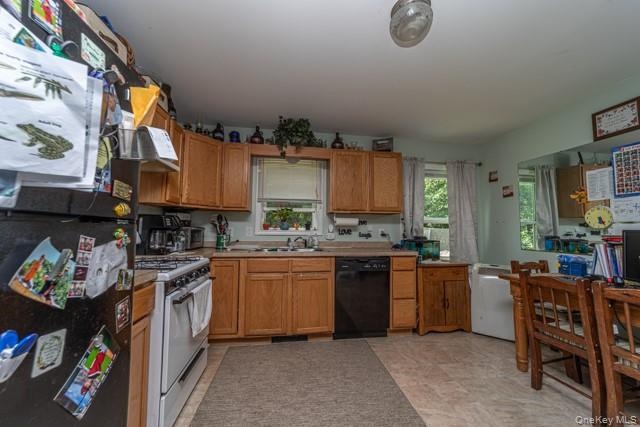 Kitchen featuring wood cabinetry, a white gas range, and a black dishwasher