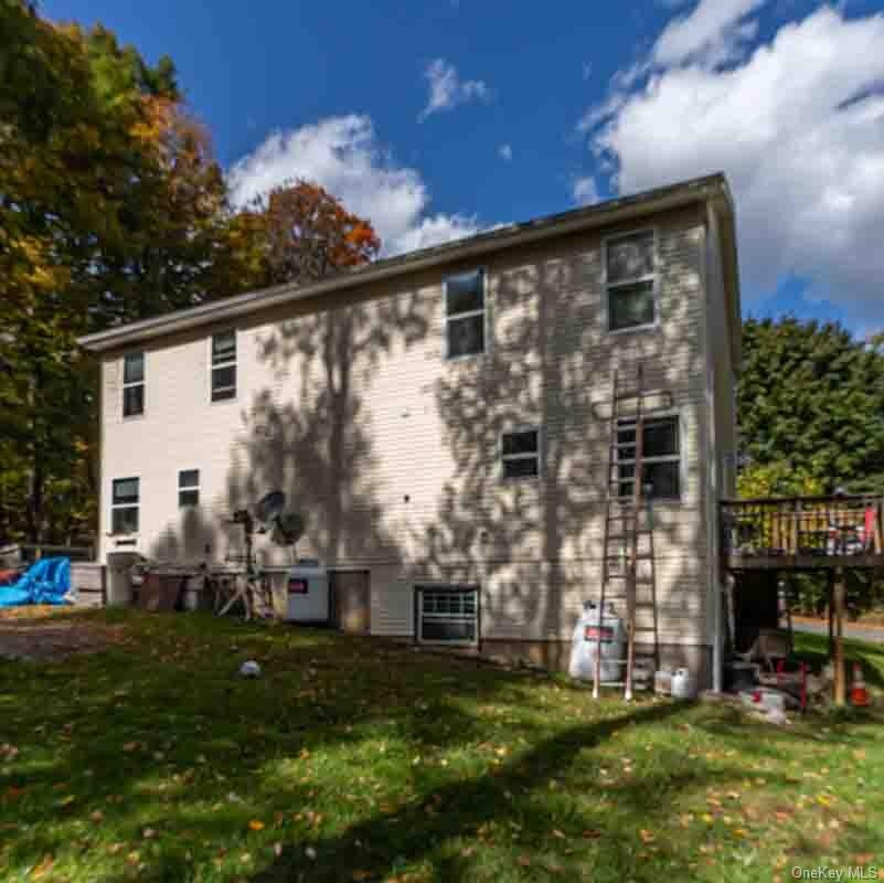 Two-story exterior with light-colored siding, multiple windows, and a raised wooden deck