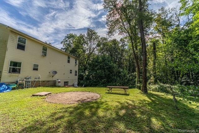 Expansive grassy yard with mature trees and a circular gravel patio area