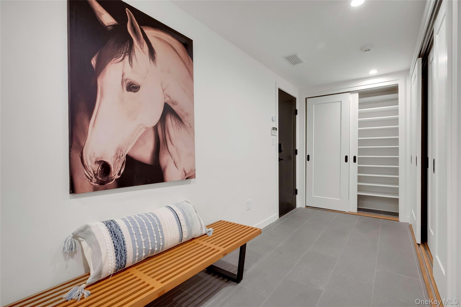 Spacious, beautifully organized mudroom with a full wall of custom storage closets, tucked behind stylish barn doors.