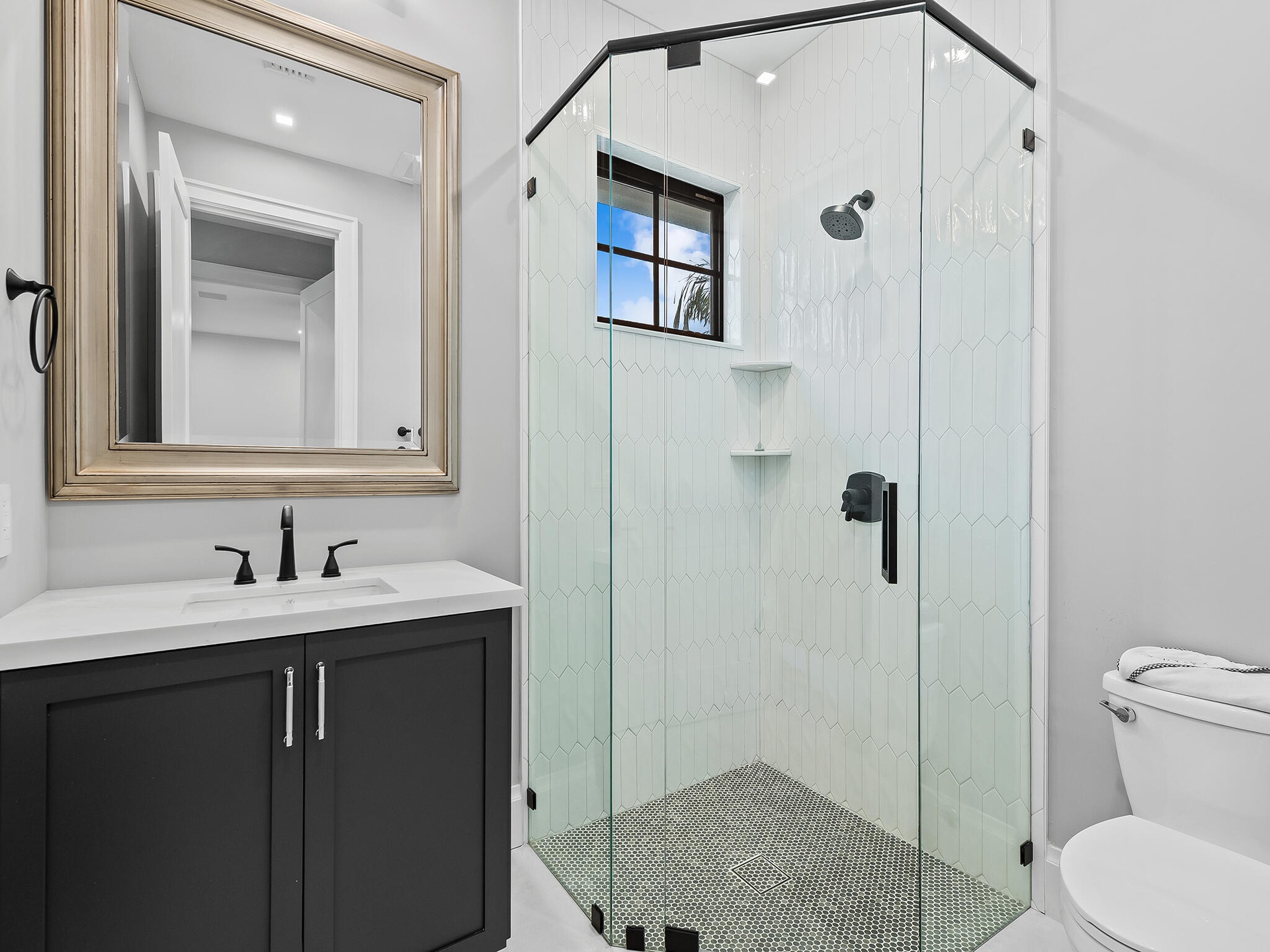 Guest bathroom with glass shower and dark vanity