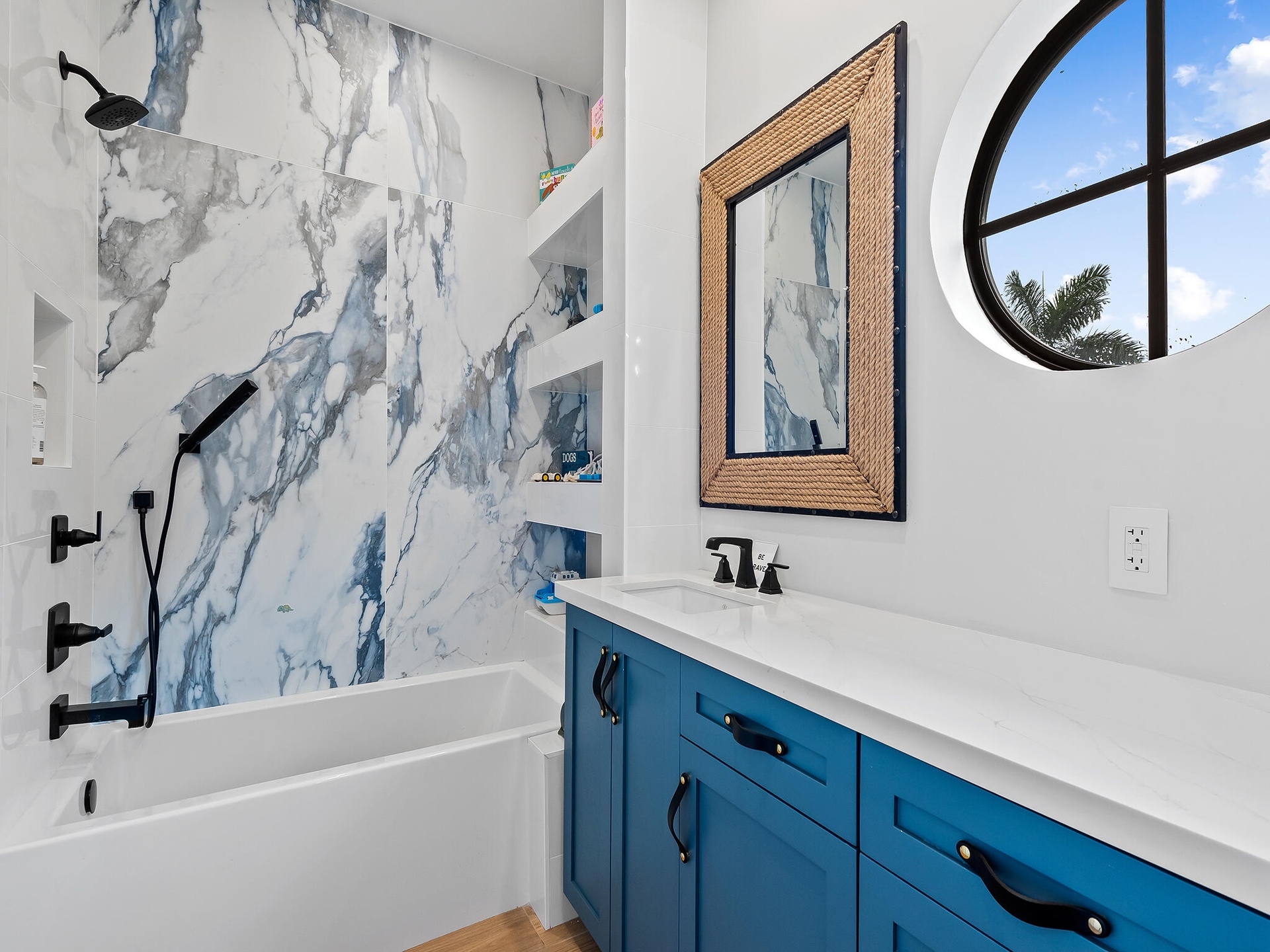 Bathroom with blue vanity and round window