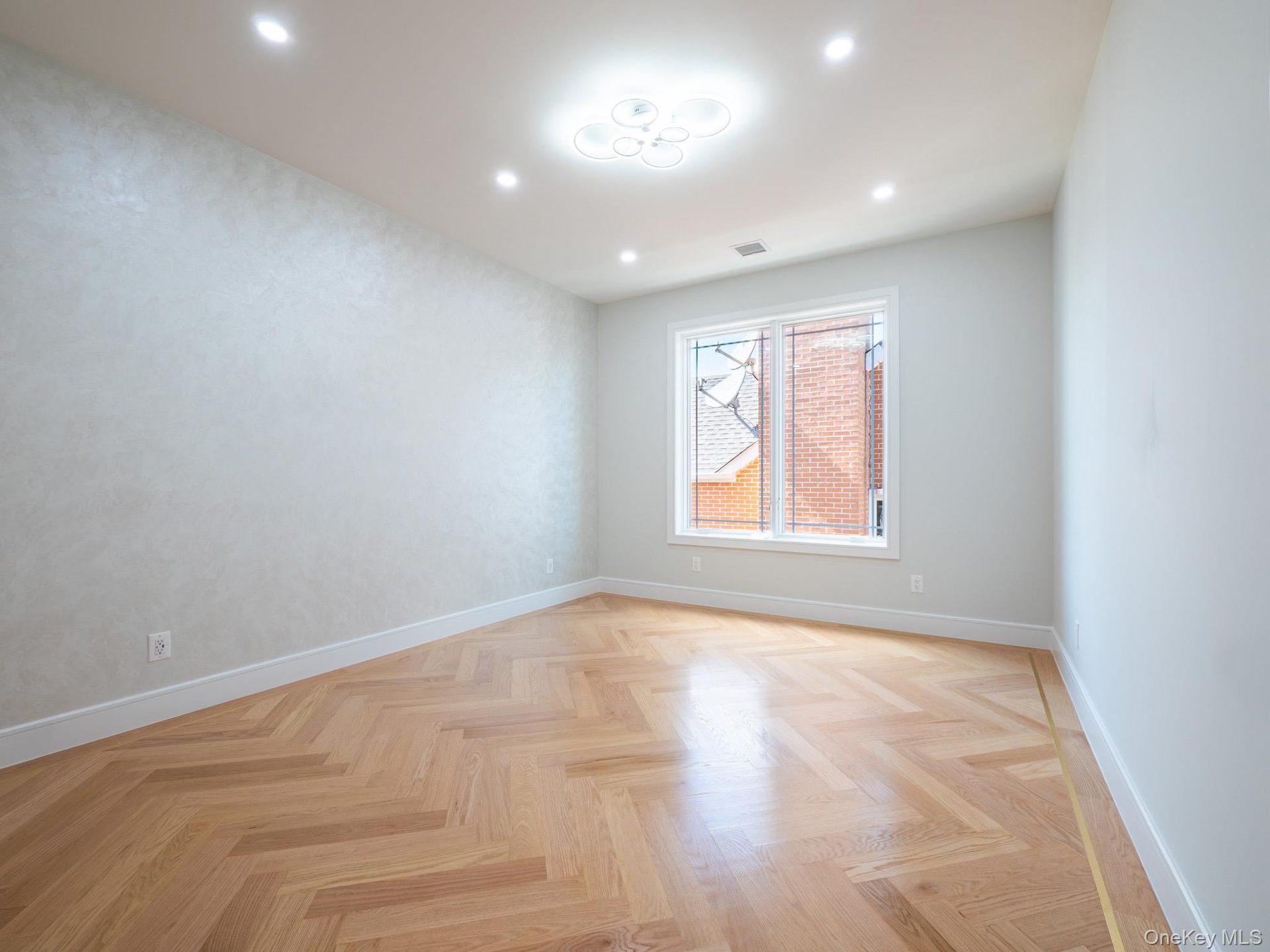 Herringbone wood-finish flooring, recessed ceiling lighting, a modern ceiling fixture, and a large window