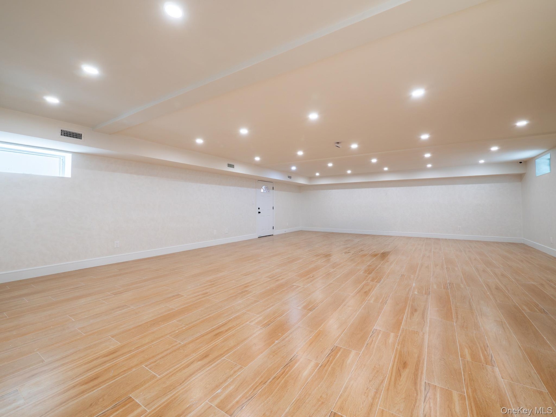 Spacious finished area featuring wood-finish flooring, recessed lighting, and white walls