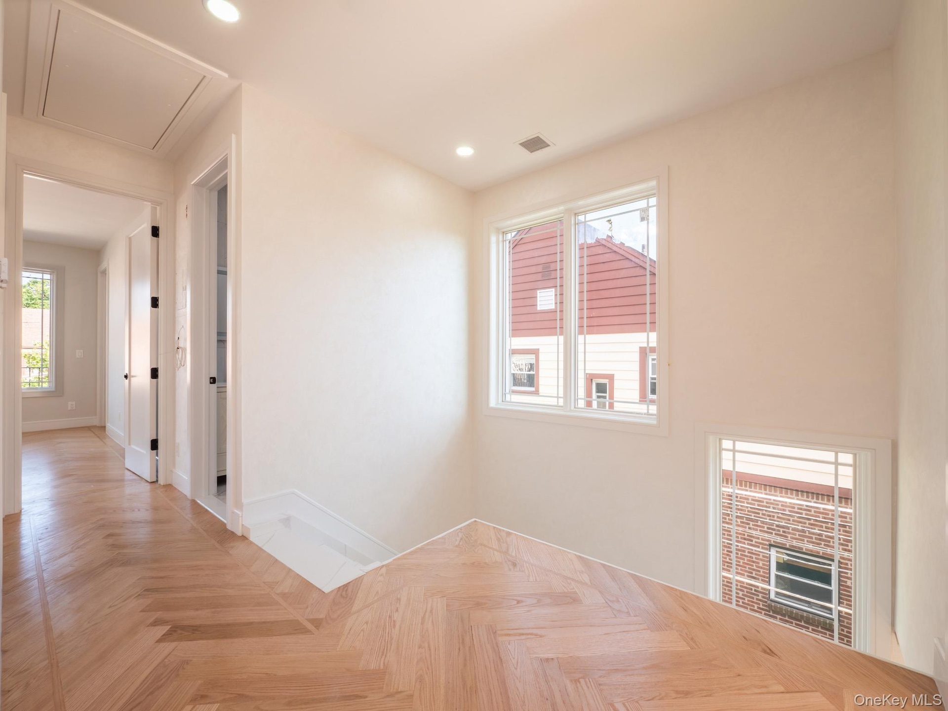Herringbone wood-finish flooring, recessed lighting, and white walls