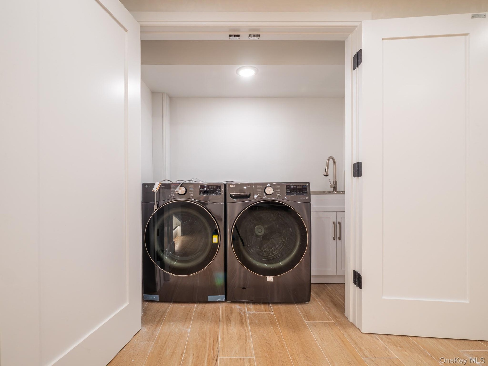Laundry area featuring wood-finish flooring and a utility sink with a gooseneck faucet