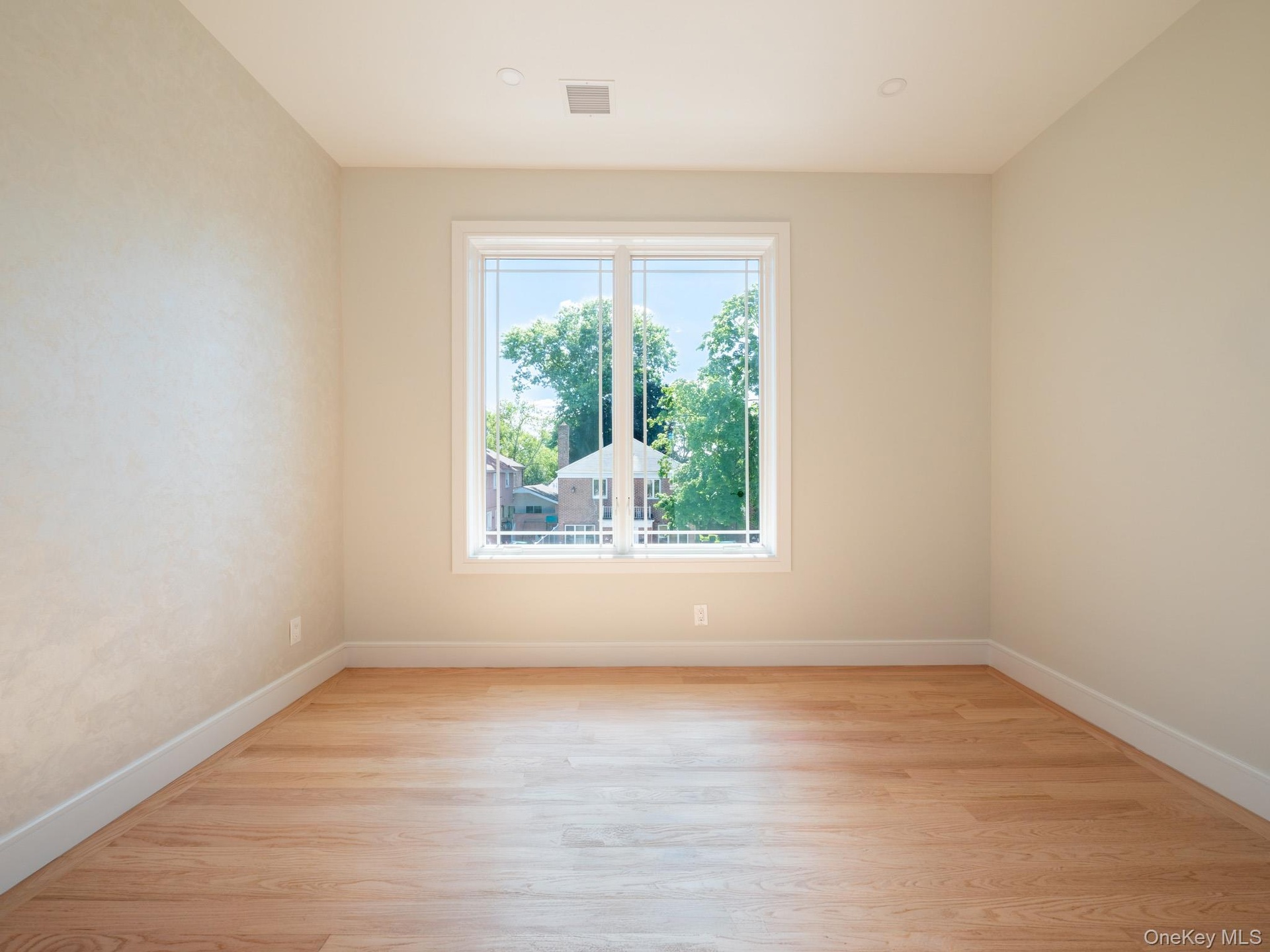 Hardwood-style flooring, white trim, recessed lighting, and a large window