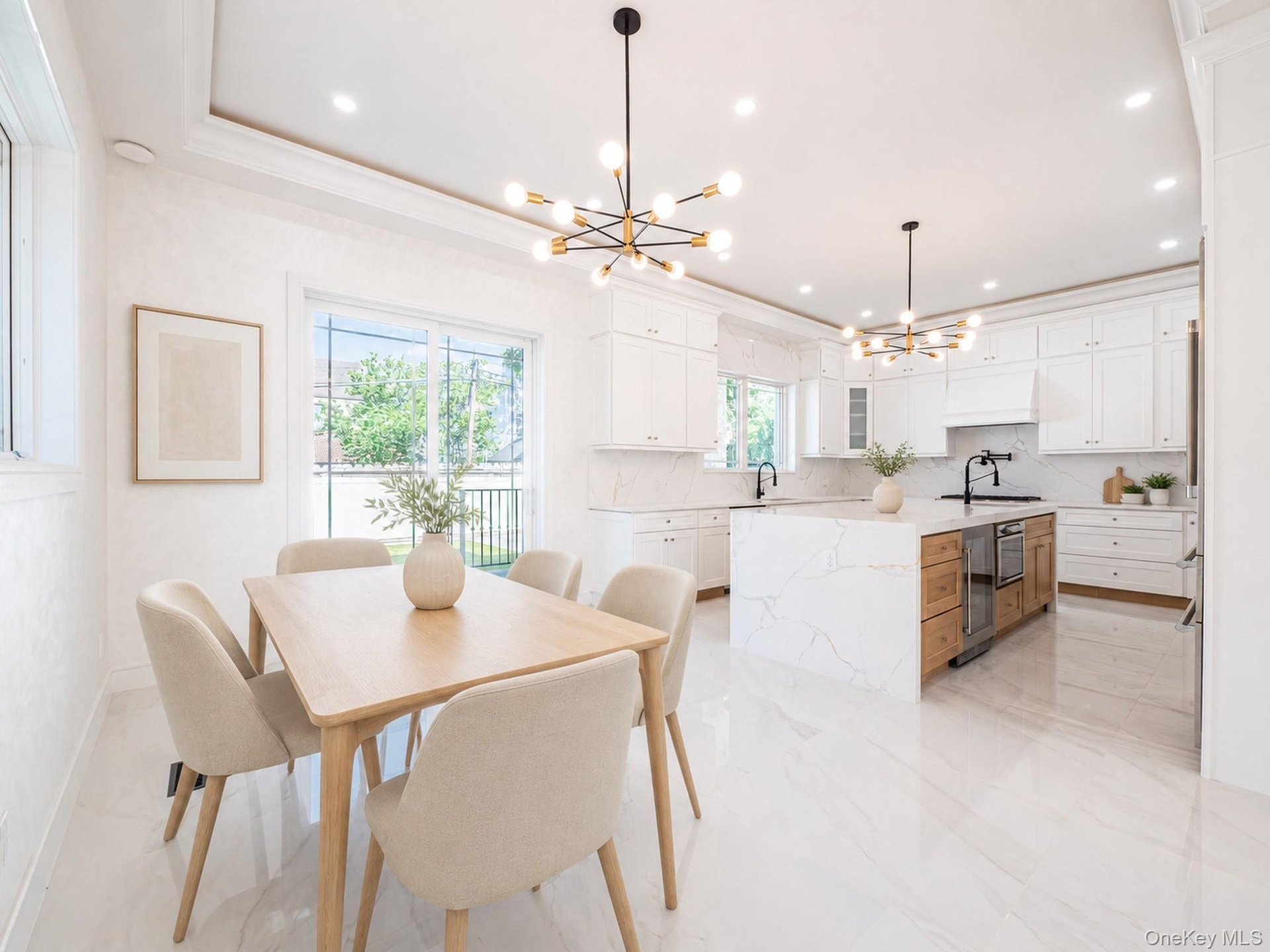 Open-concept kitchen and dining area featuring white cabinetry, a kitchen island with integrated appliances and wood-finish drawers, and sleek tile fl