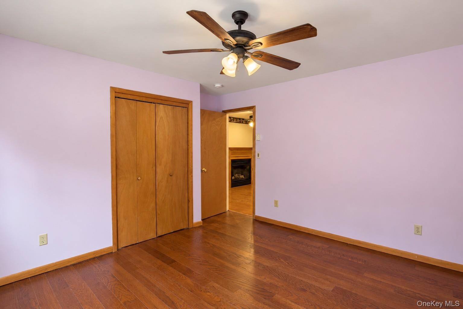 Wood-finish flooring, ceiling fan with integrated lighting, wood-paneled bi-fold closet, and recessed doorway