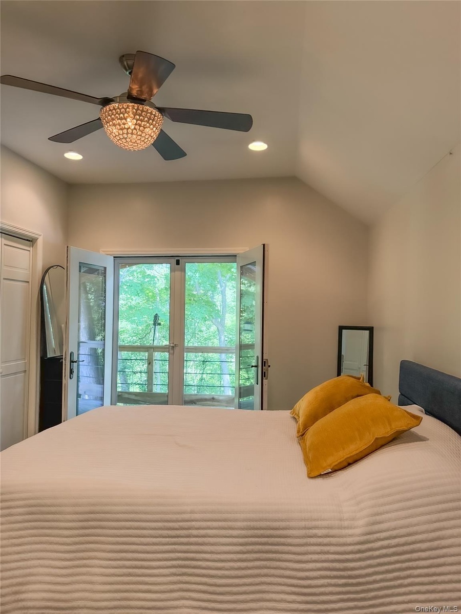 Cottage bedroom with vaulted ceiling with recessed lighting, a decorative ceiling fan, and French doors that leads to private  deck