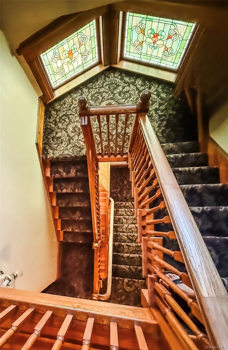 Staircase with wood banisters and balusters, carpeted tread and Stained glass windows