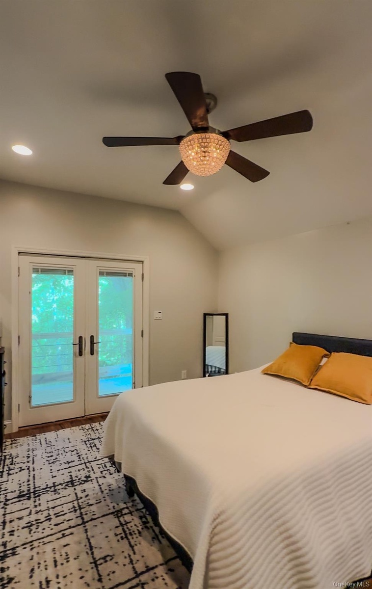 Cottage bedroom with vaulted ceiling with recessed lighting, a decorative ceiling fan, and French doors that leads to private  deck