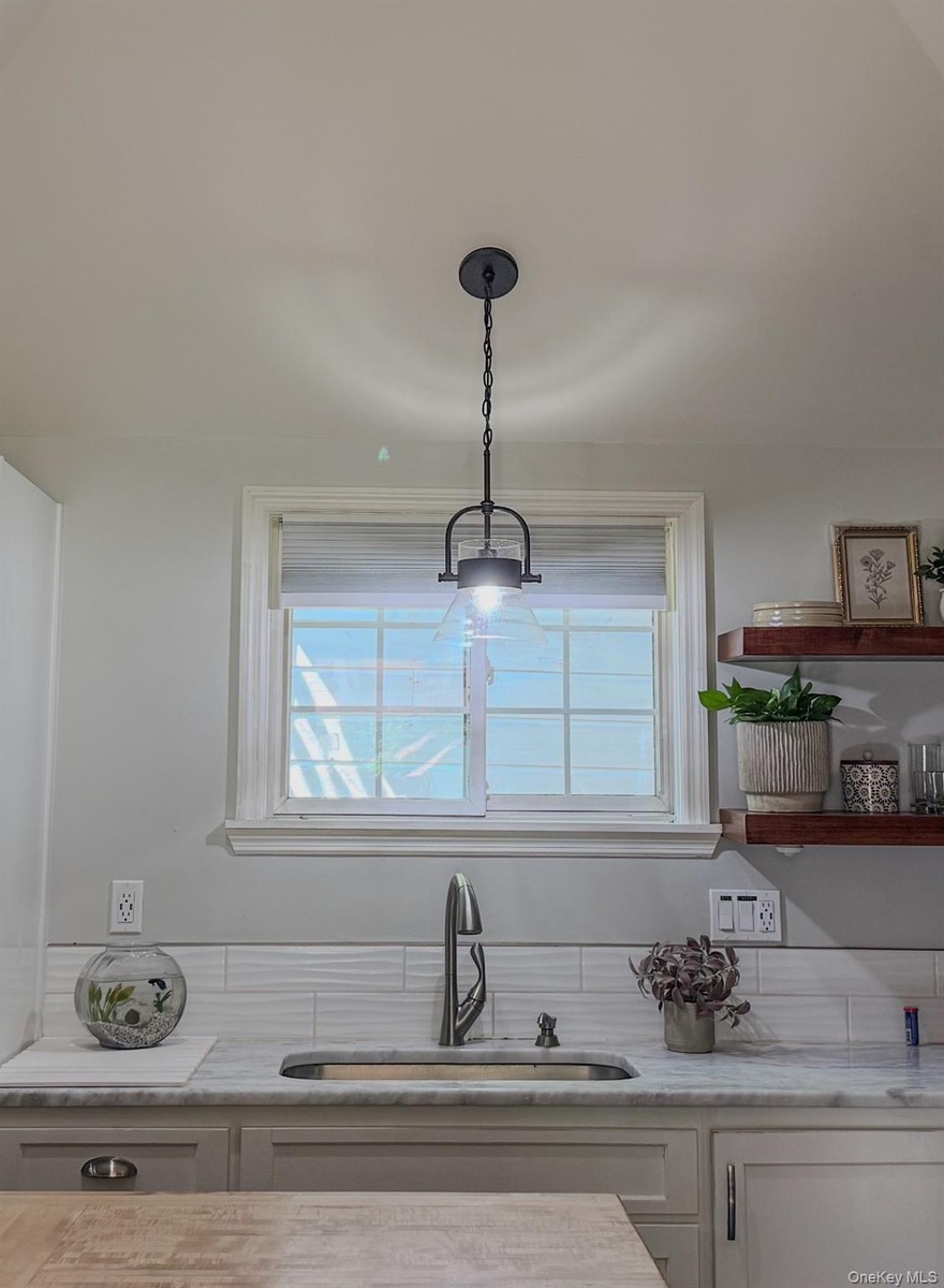Cottage kitchen featuring a central island with white shaker cabinetry, stainless steel appliances, and open wood shelving