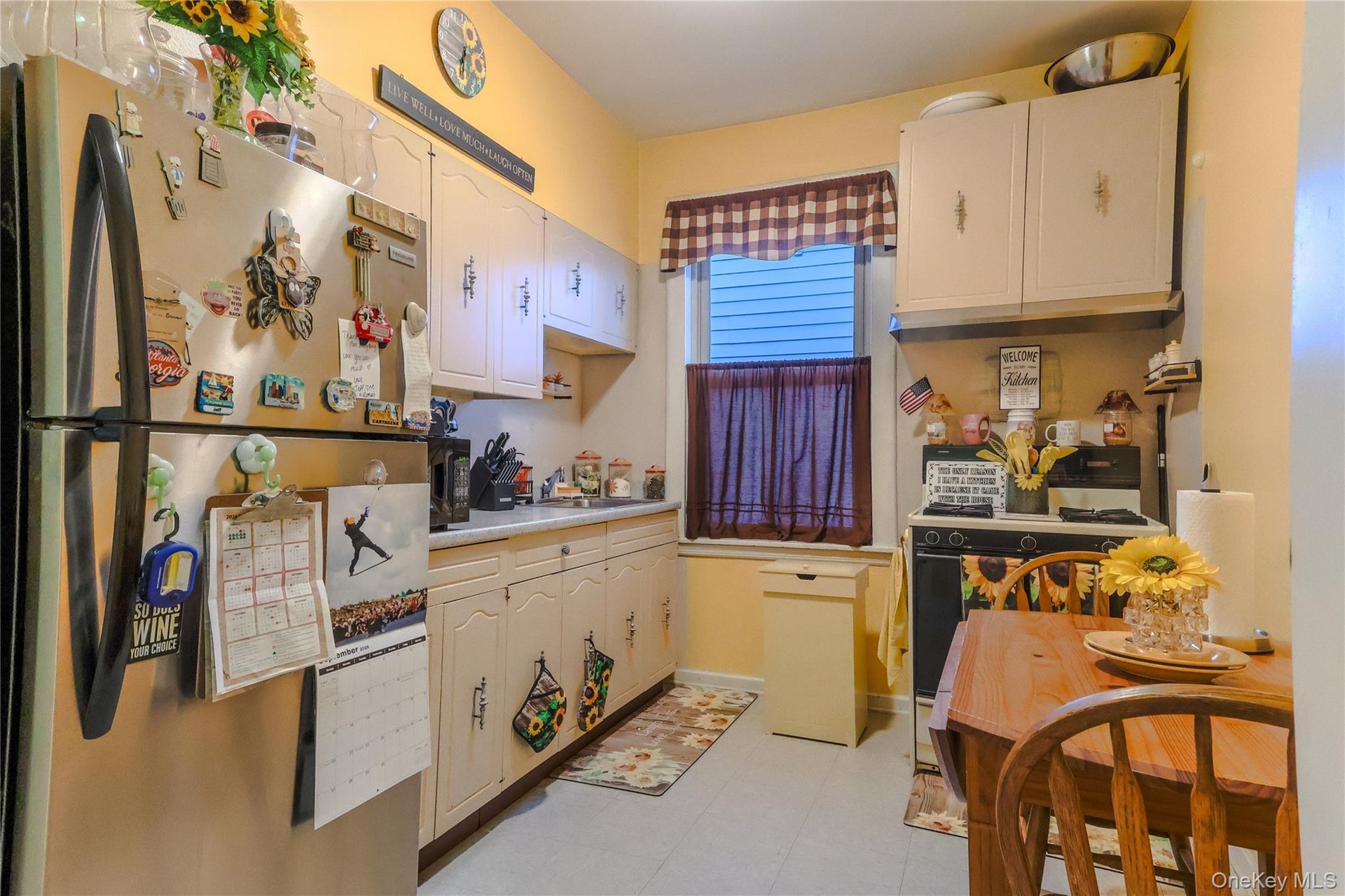 Kitchen featuring a stainless steel refrigerator, cream-colored cabinetry, and a window