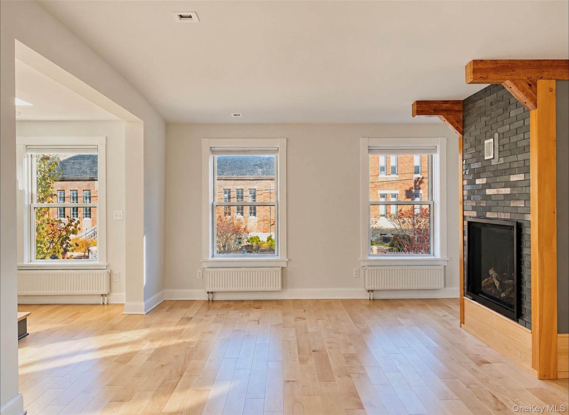Apartment living room with gas fireplace, maple floors throughout and beautiful views of the Armory.