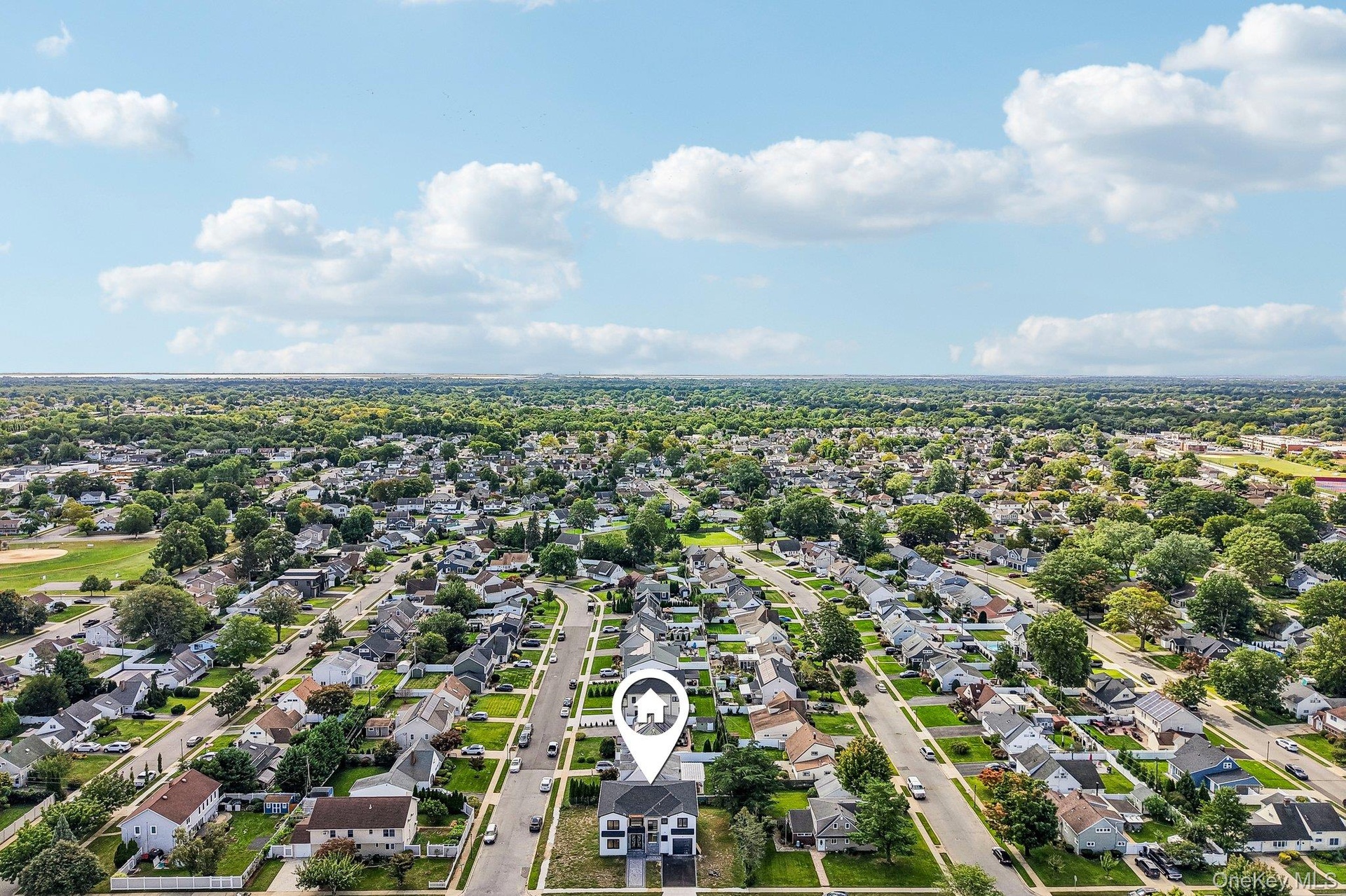Expansive residential area featuring numerous single-family homes, mature trees lining streets, and visible athletic fields