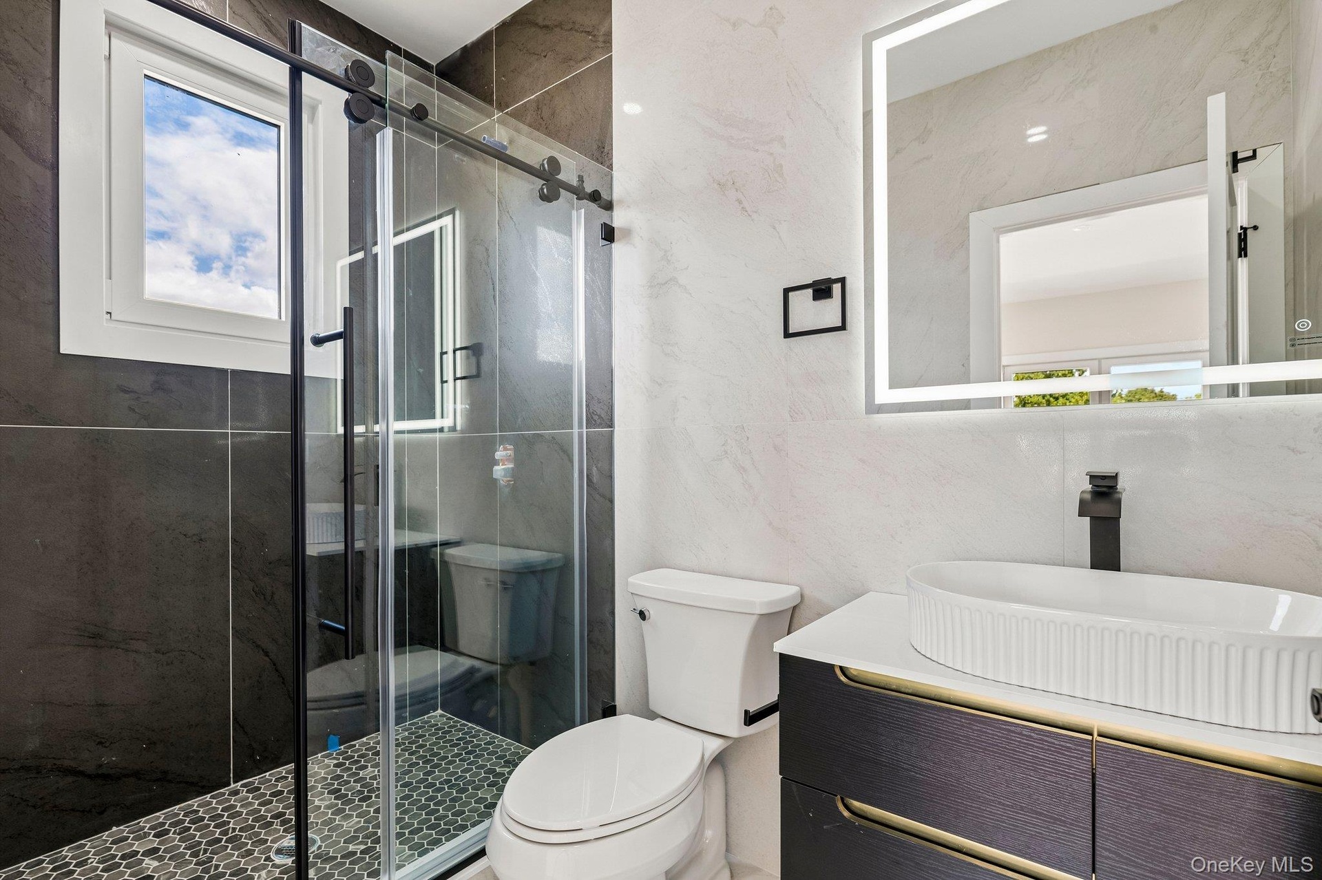 Contemporary bathroom featuring a sliding glass shower door, a large rectangular illuminated mirror, a vessel sink, dark wood-finish cabinetry, and a 