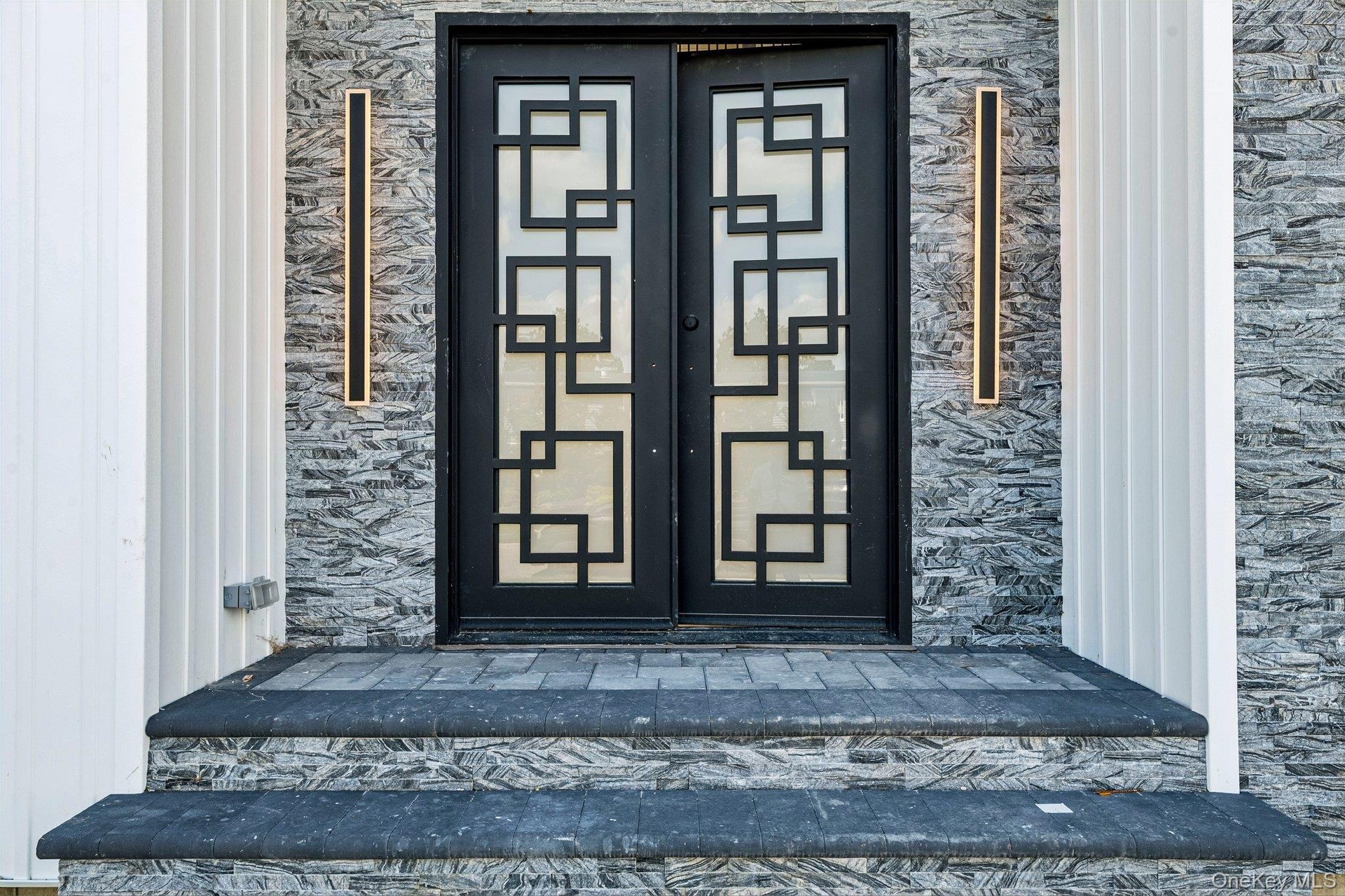 Double-door entry featuring geometric glass inserts and black framing