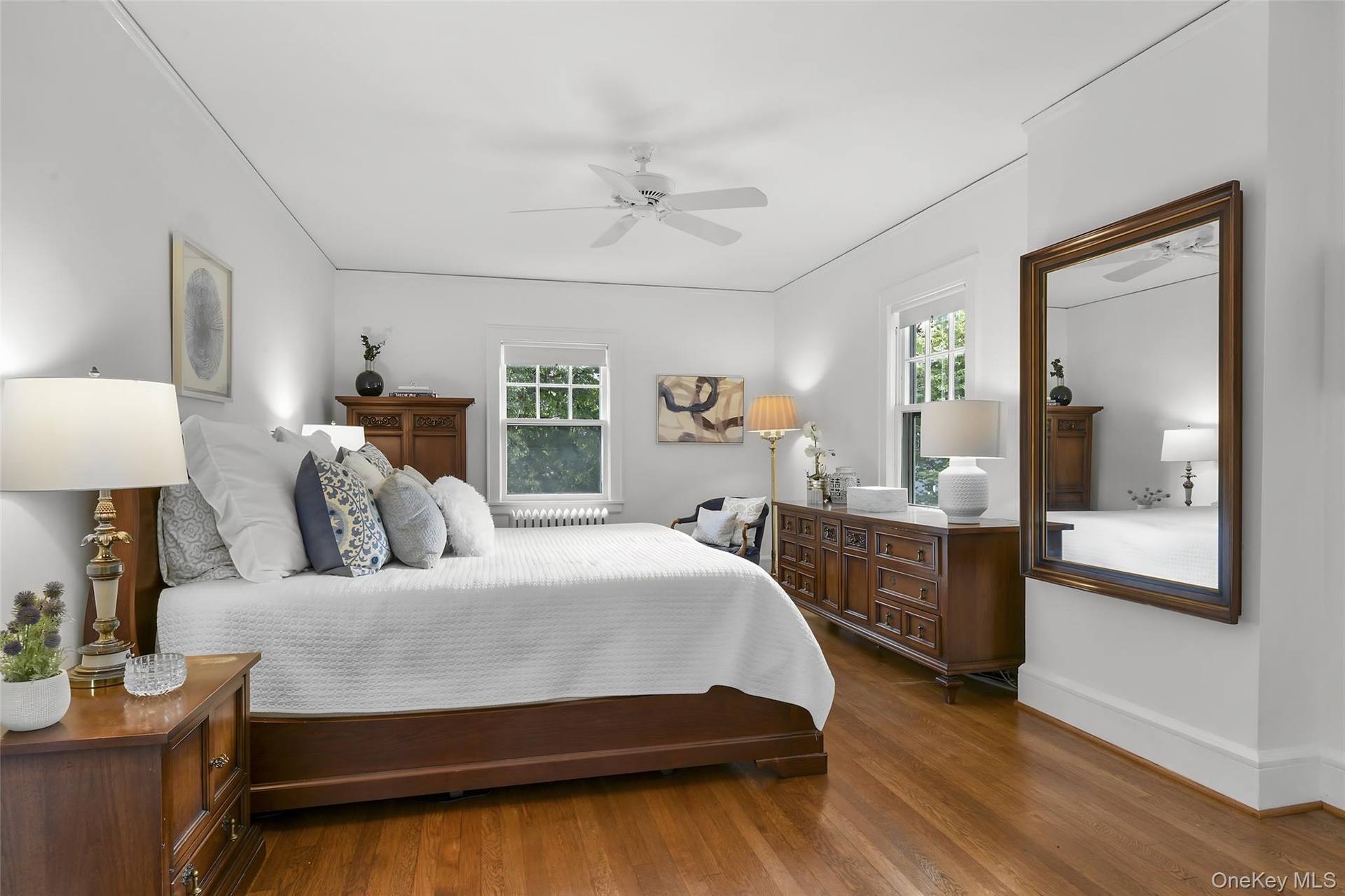Primary bedroom suite with hardwood floors and ceiling fan.